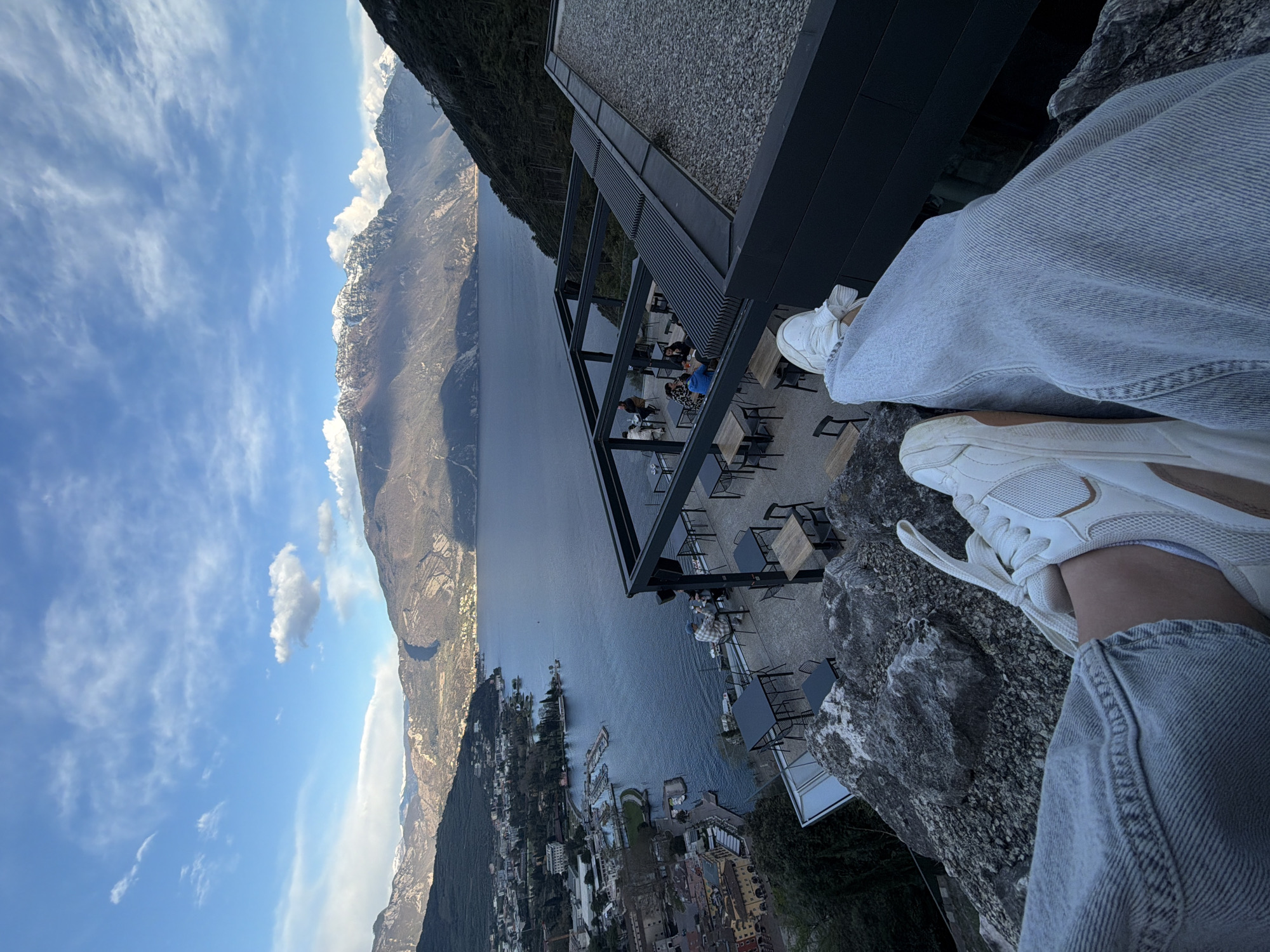 Person sits on rocks near modern building in Riva del Garda