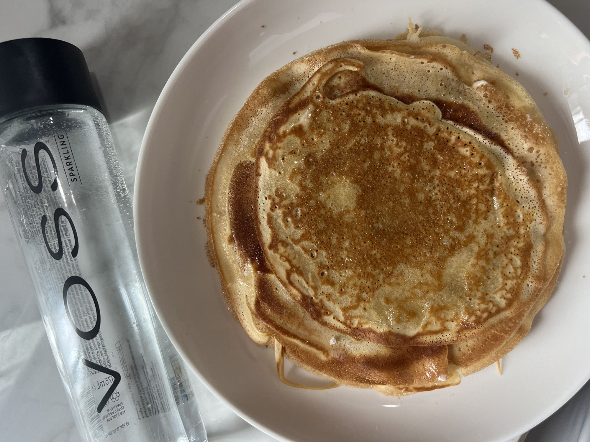 Pancakes and VOSS water styled on a marble countertop in Choeng Thale