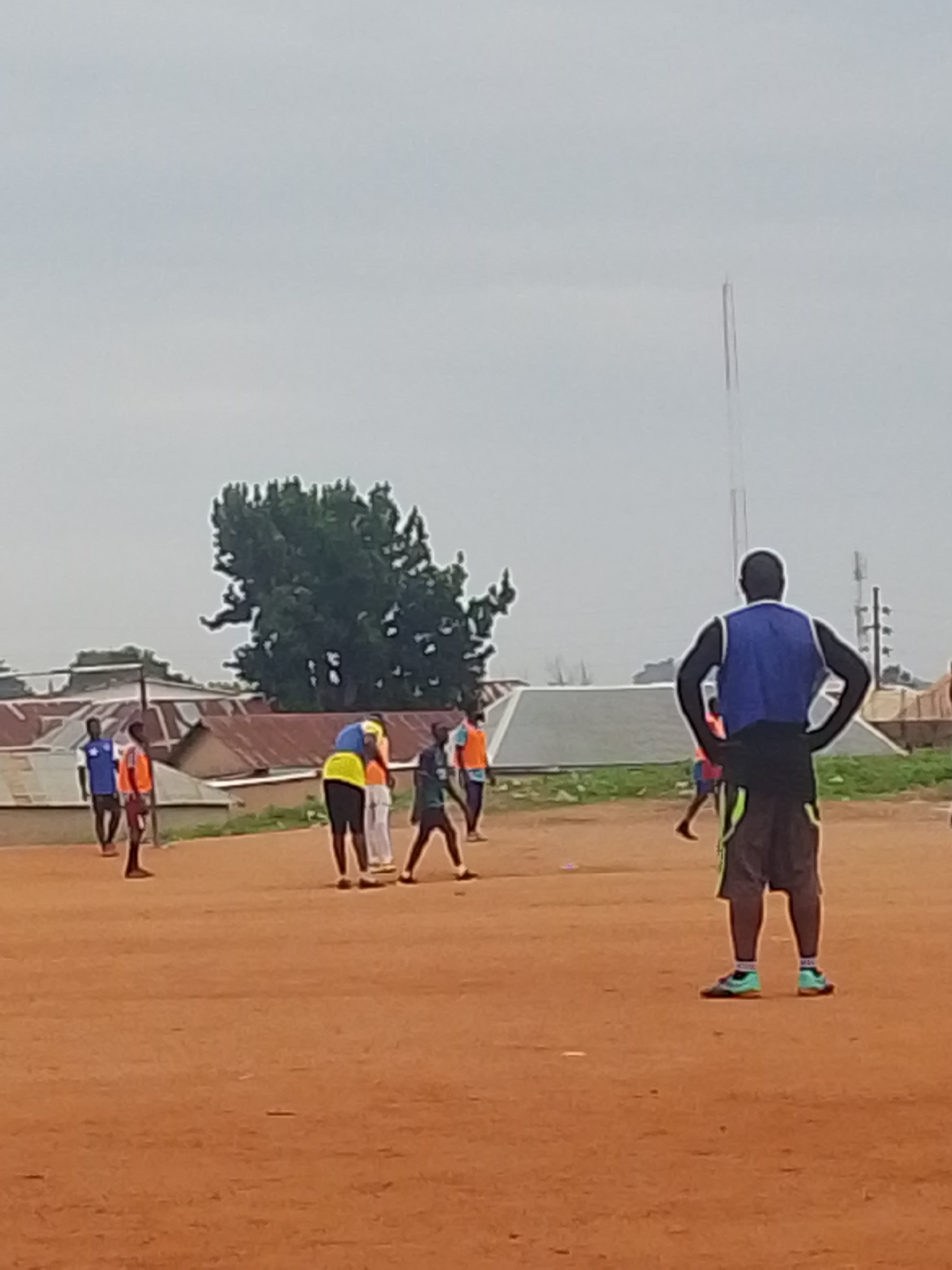 Soccer players practice on dirt field during morning hours