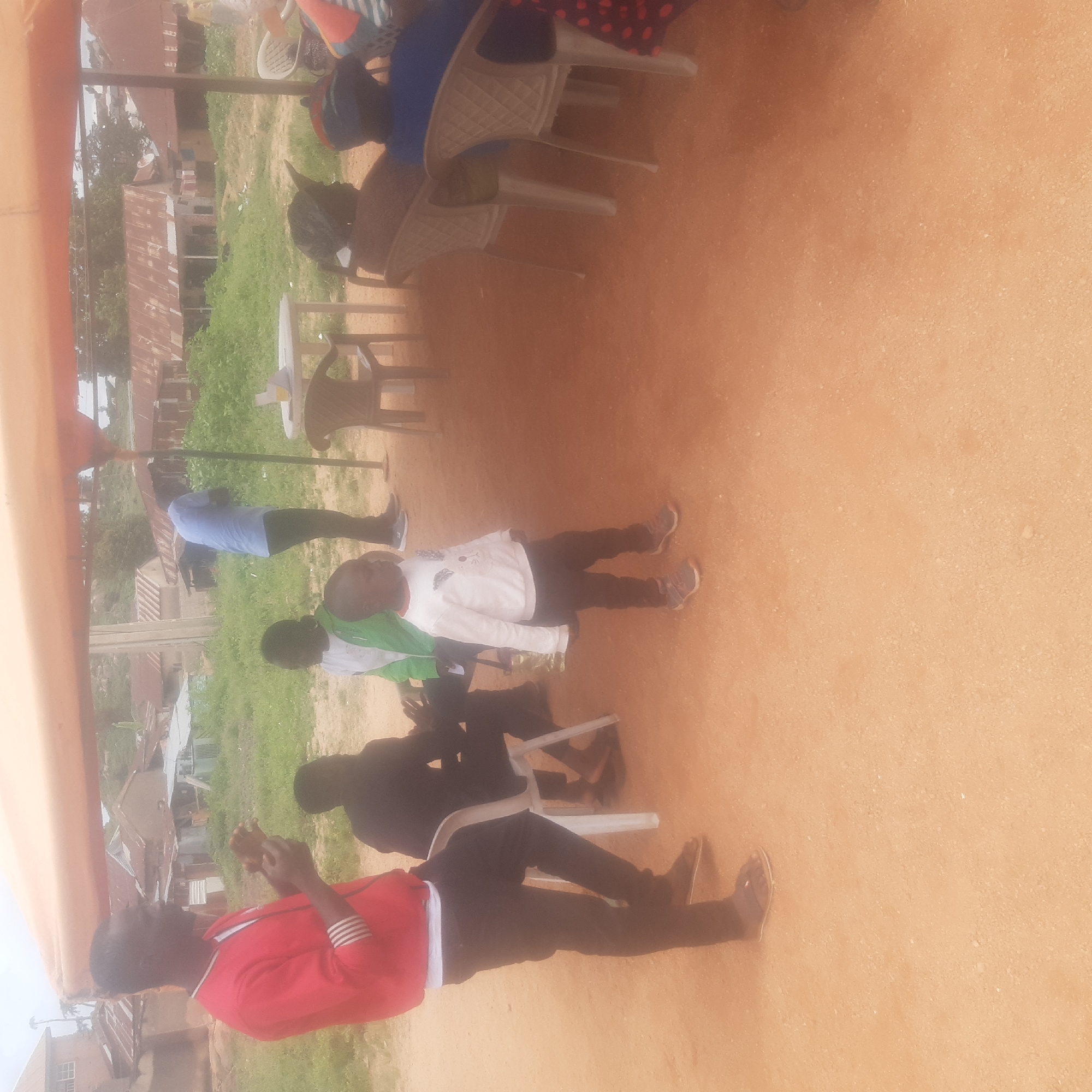 Community gathering under canopies on a dusty Jos afternoon