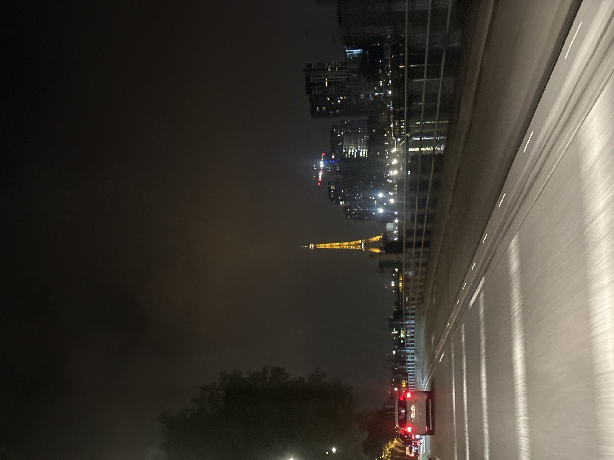 Nighttime traffic flows past illuminated Eiffel Tower in Paris