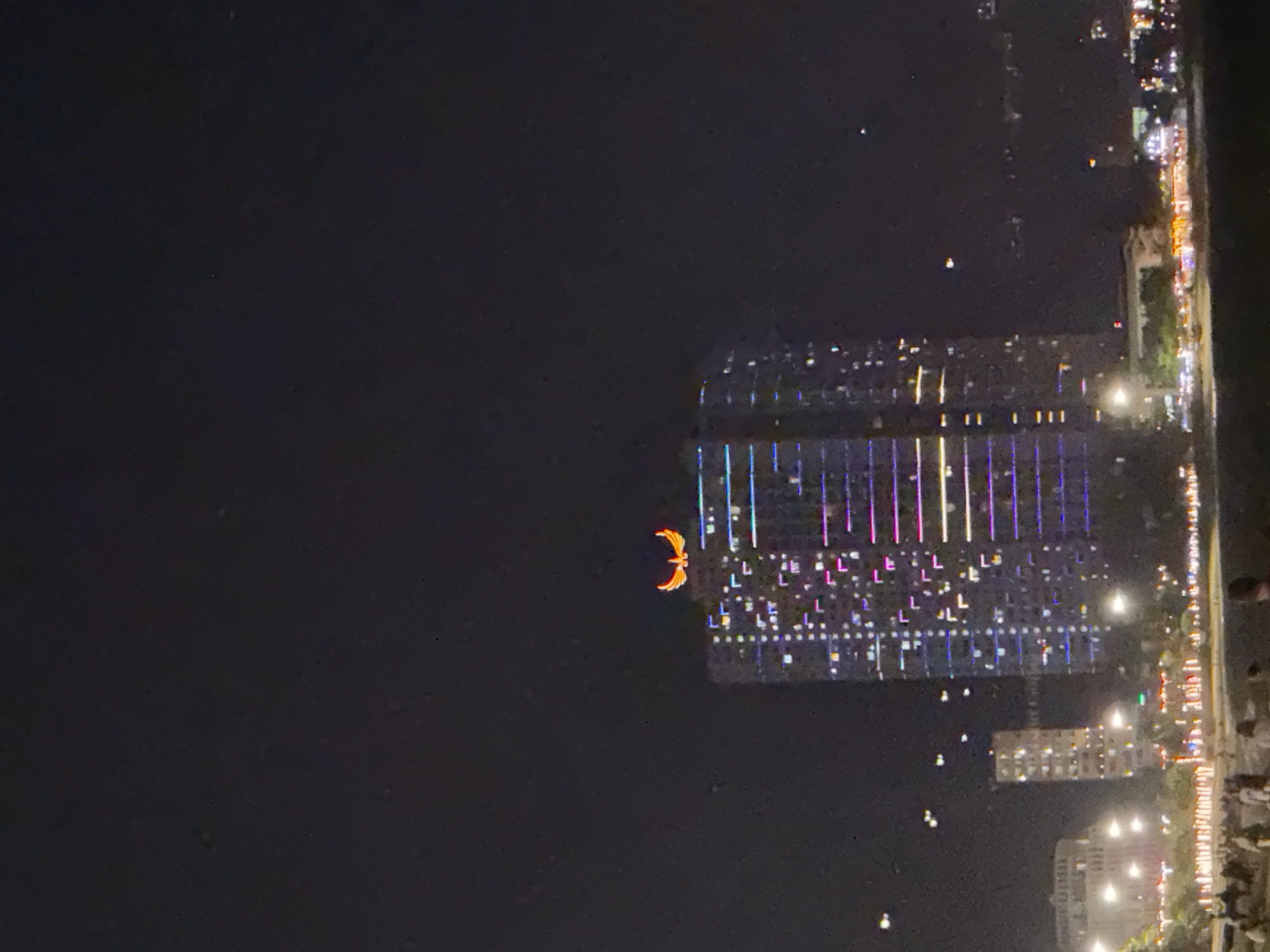 Nighttime coastal city scenes captured showing fountains, buildings, beach restaurant