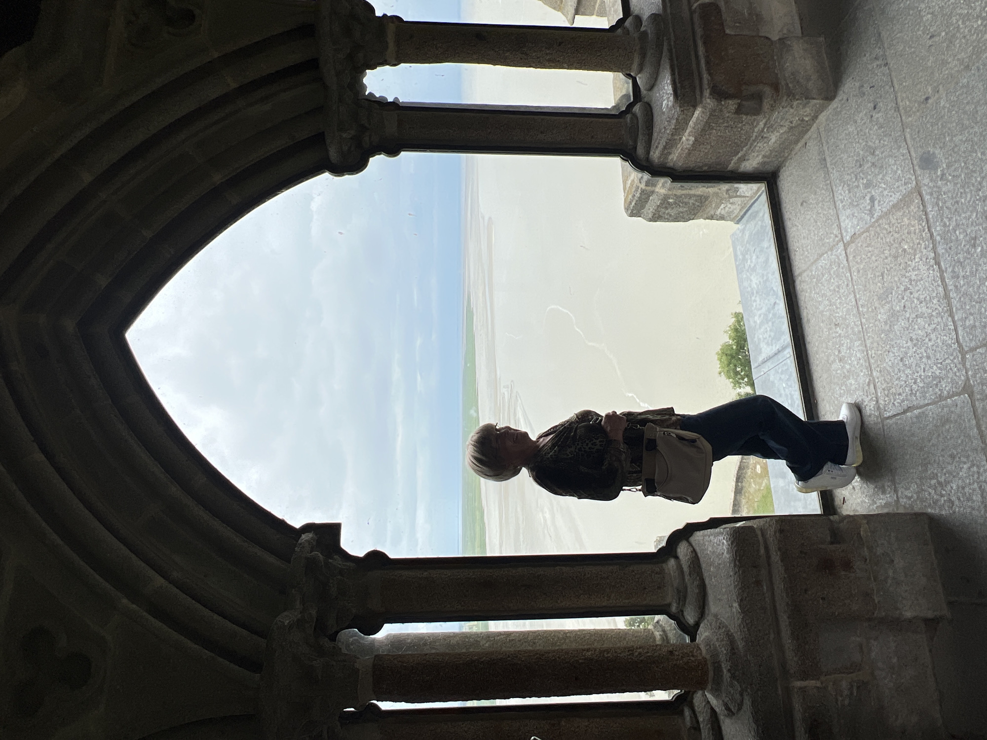 Woman silhouetted in stone archway observing landscape in Hirel