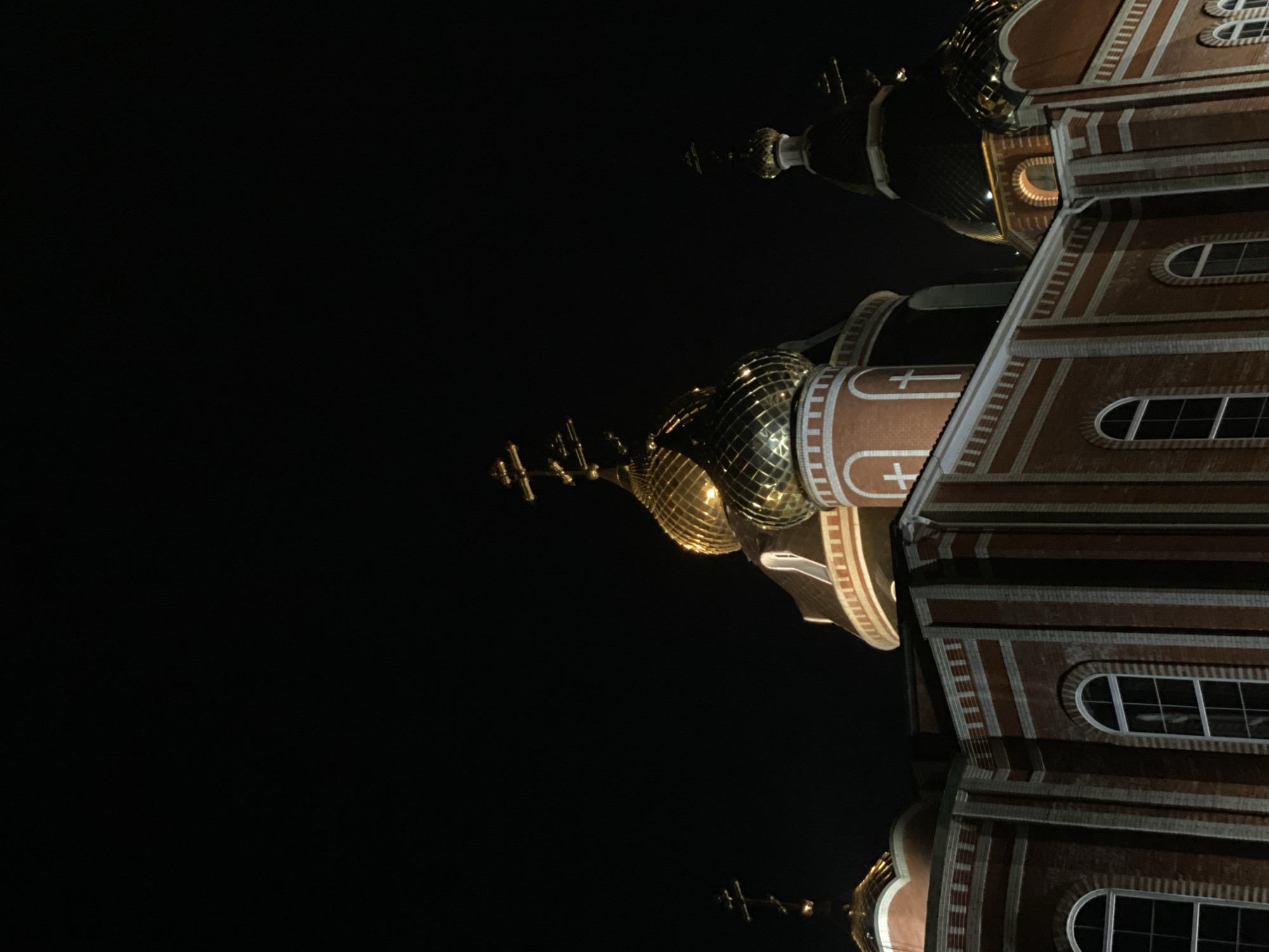 Orthodox church with golden domes observed illuminated at night