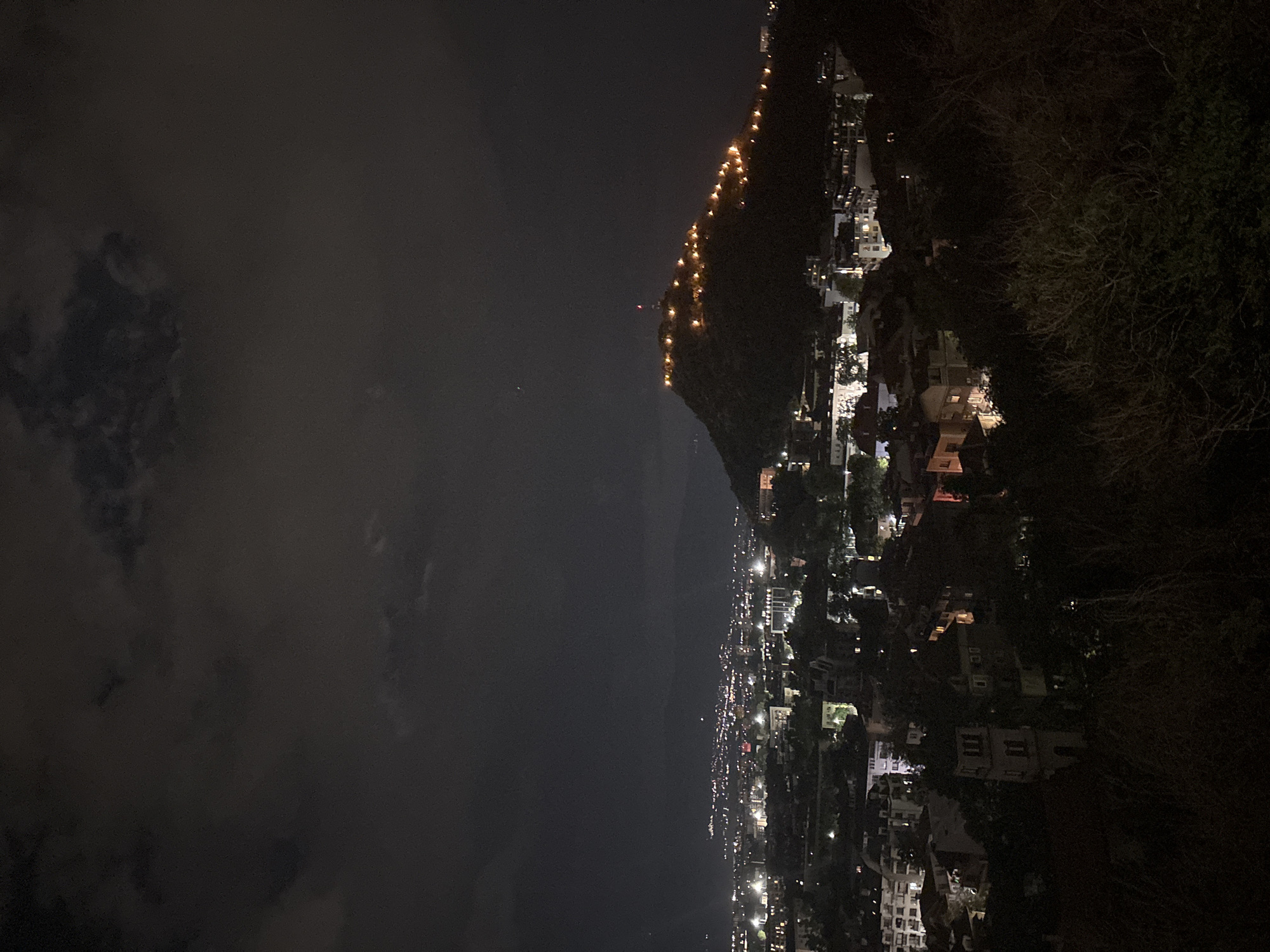 Coastal hillside town glows faintly in the night