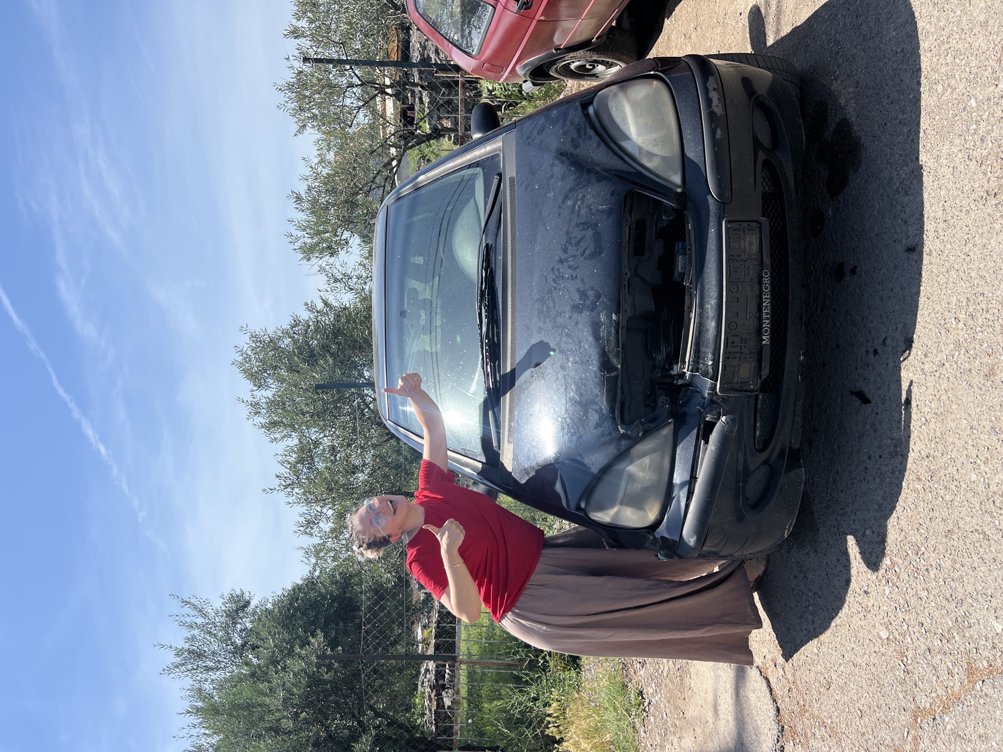 Woman stands beside heavily damaged Mercedes in Podgorica