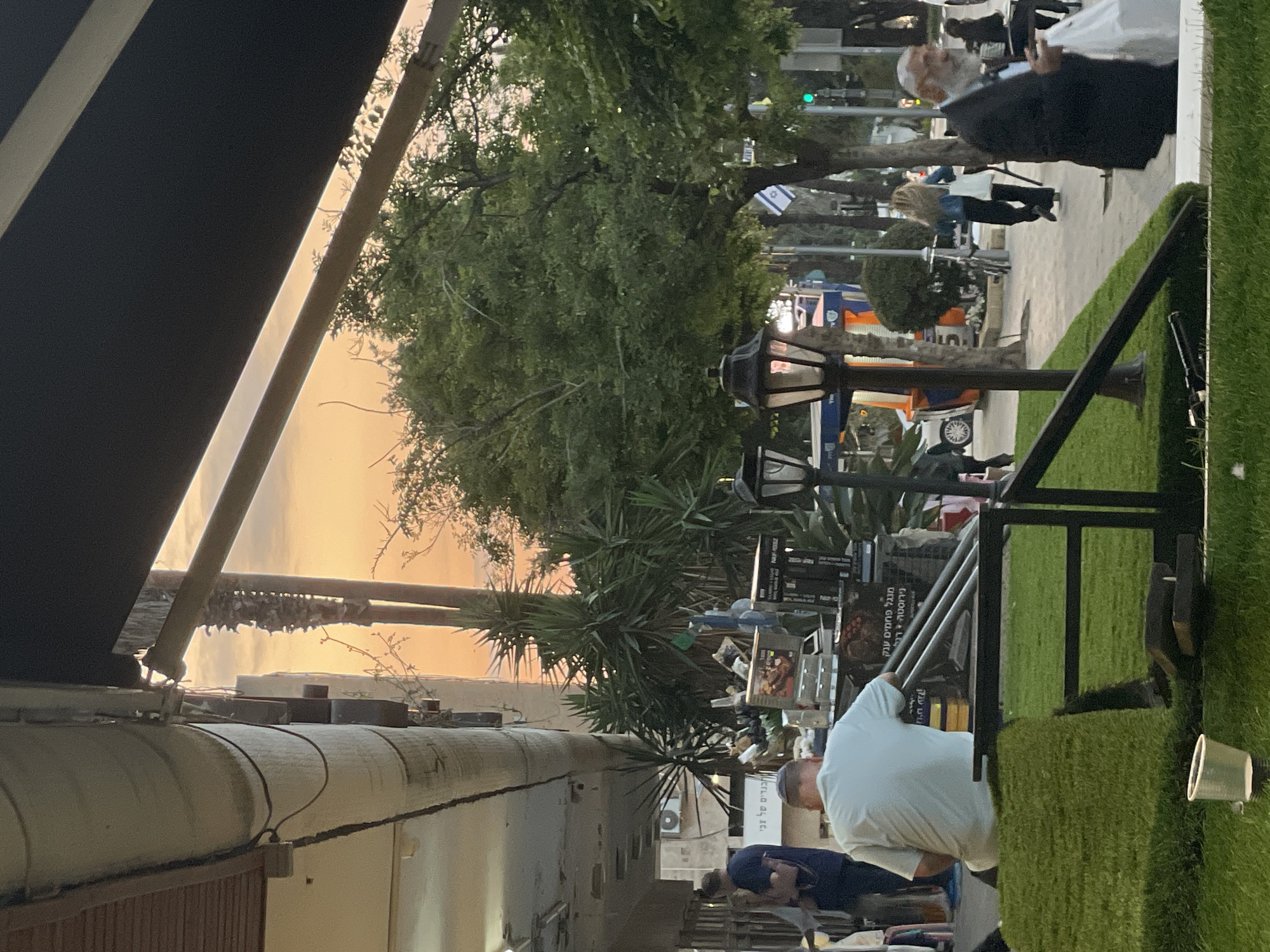 Evening gathering under awning captured in Raanana street scene