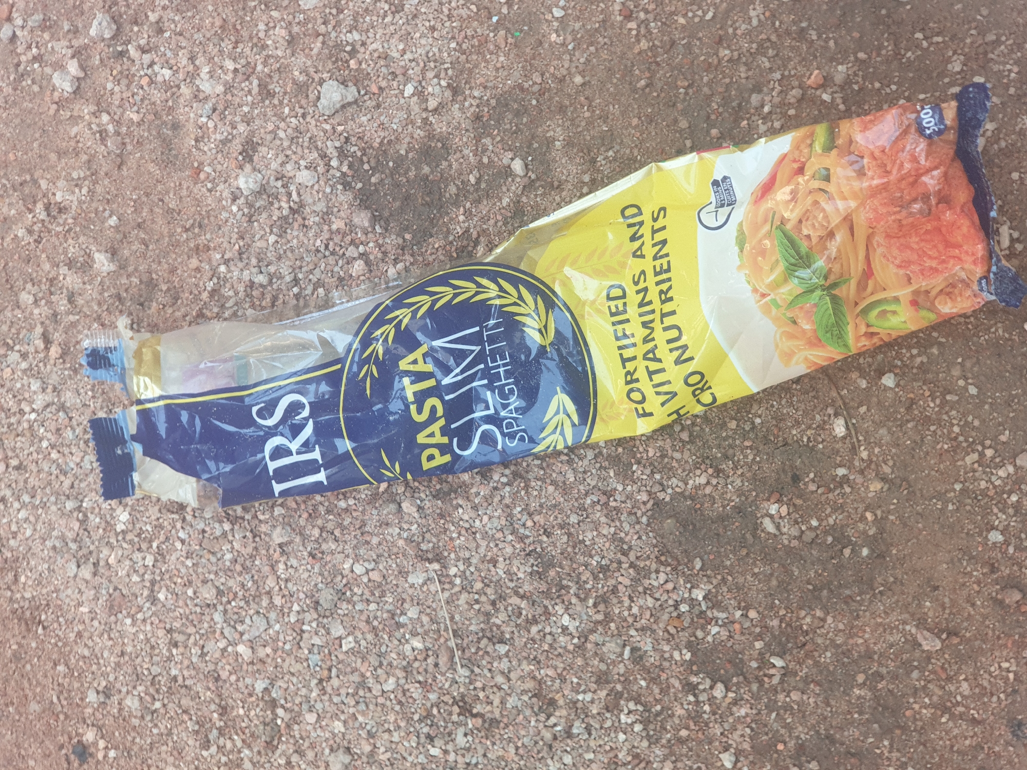 Discarded pasta snack bag spotted on rocky ground