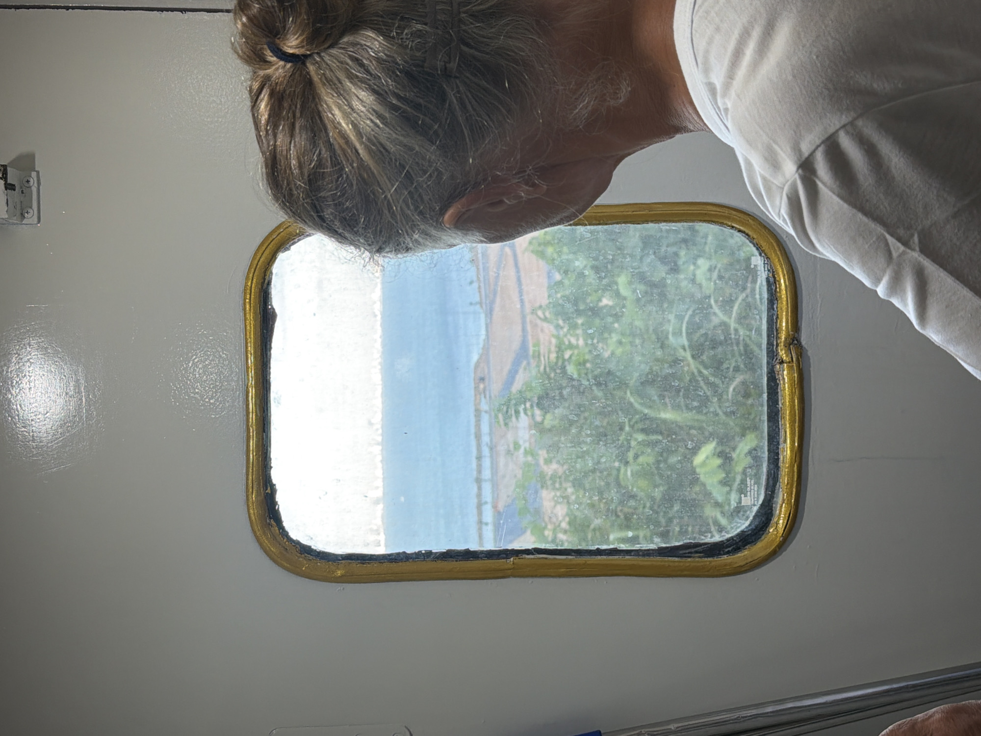 Person gazes at coastal landscape through window in Đà Nẵng