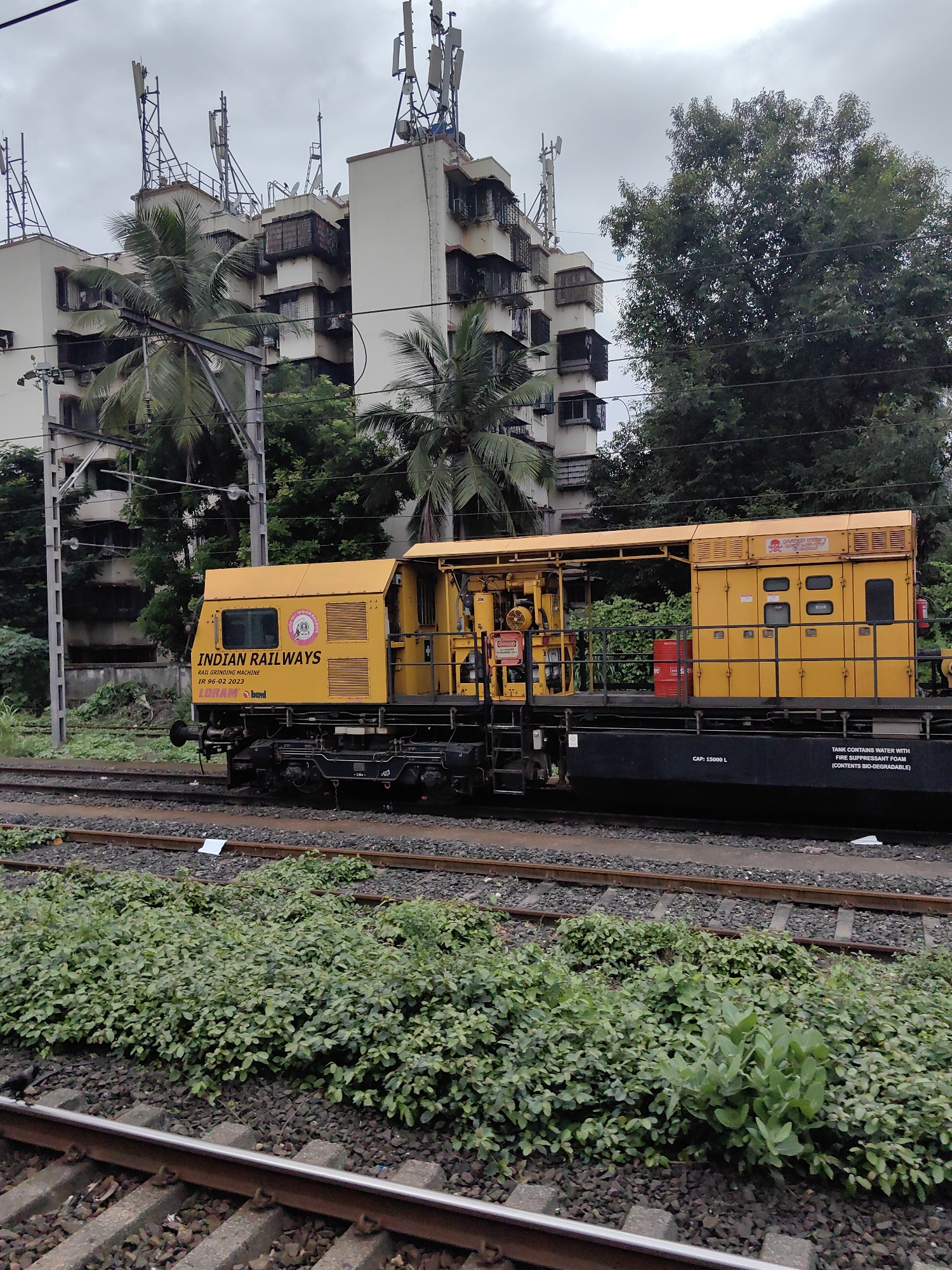 Mumbai rail traffic and maintenance equipment on a cloudy afternoon