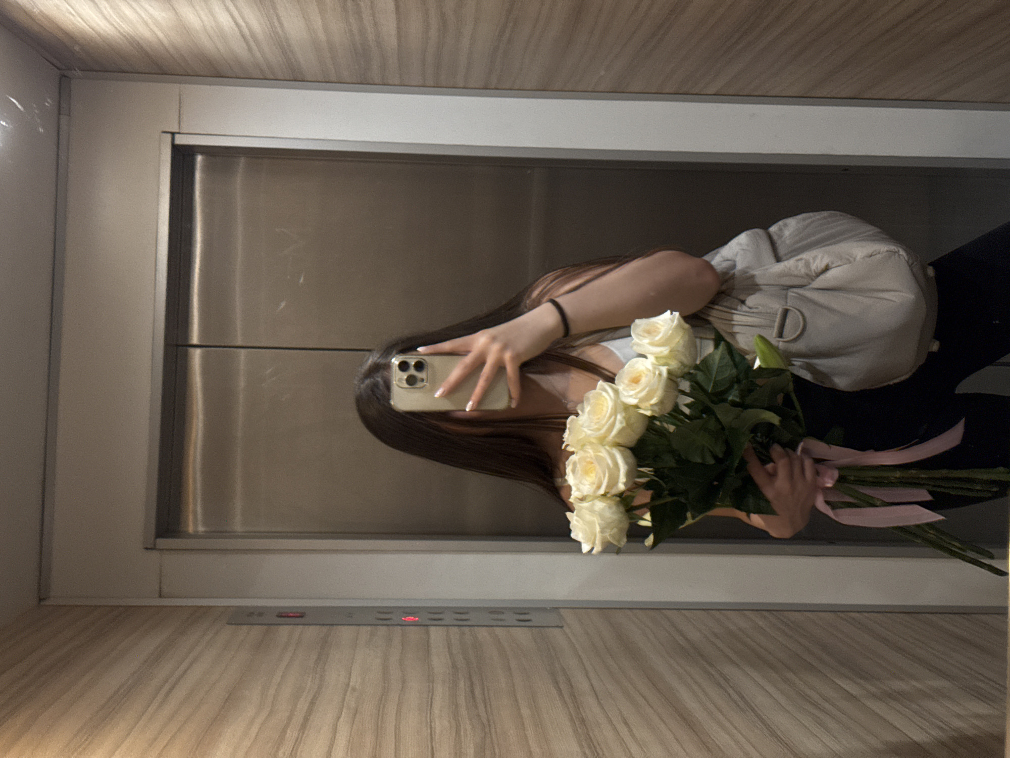 Woman takes elevator selfie with white rose bouquet in Sofia