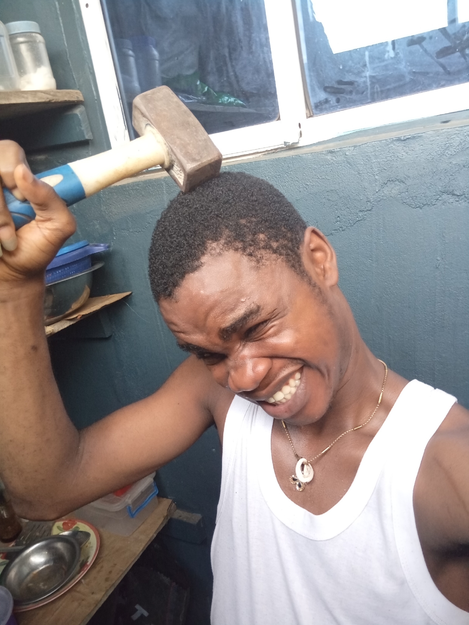 Man poses playfully with household items in Owerri kitchen
