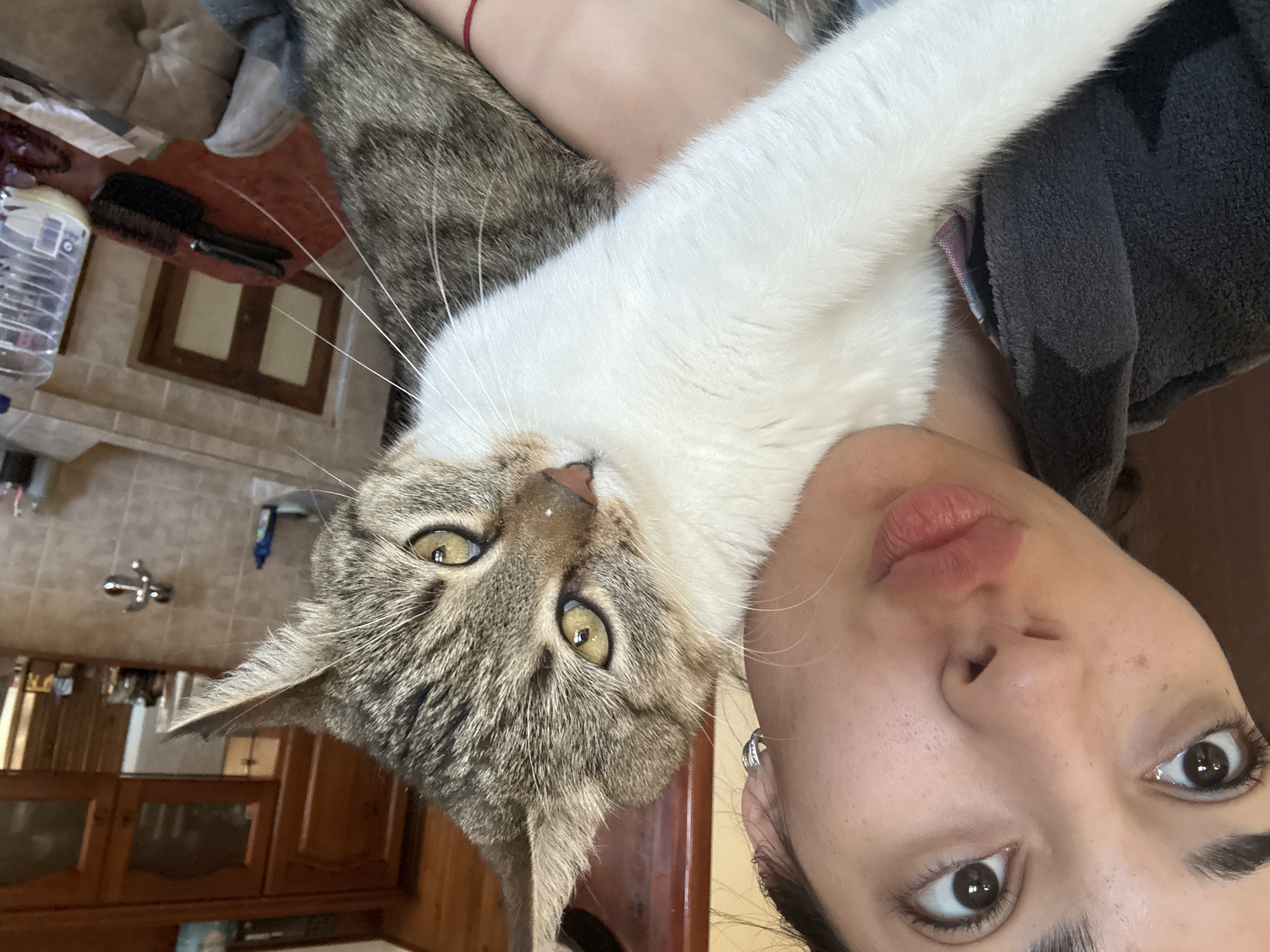 Woman poses with grey and white cat in Bulgarian home