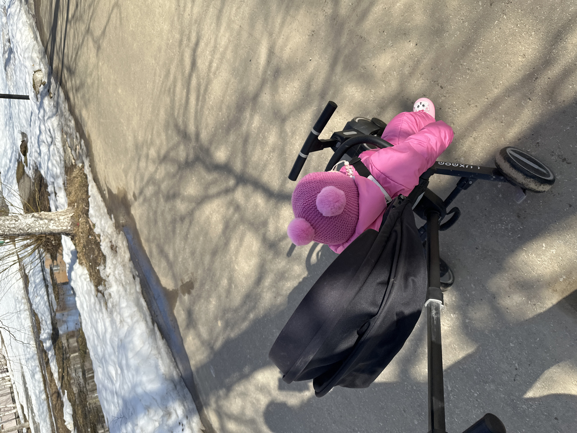 Child in pink snowsuit rides tricycle in Vuktyl