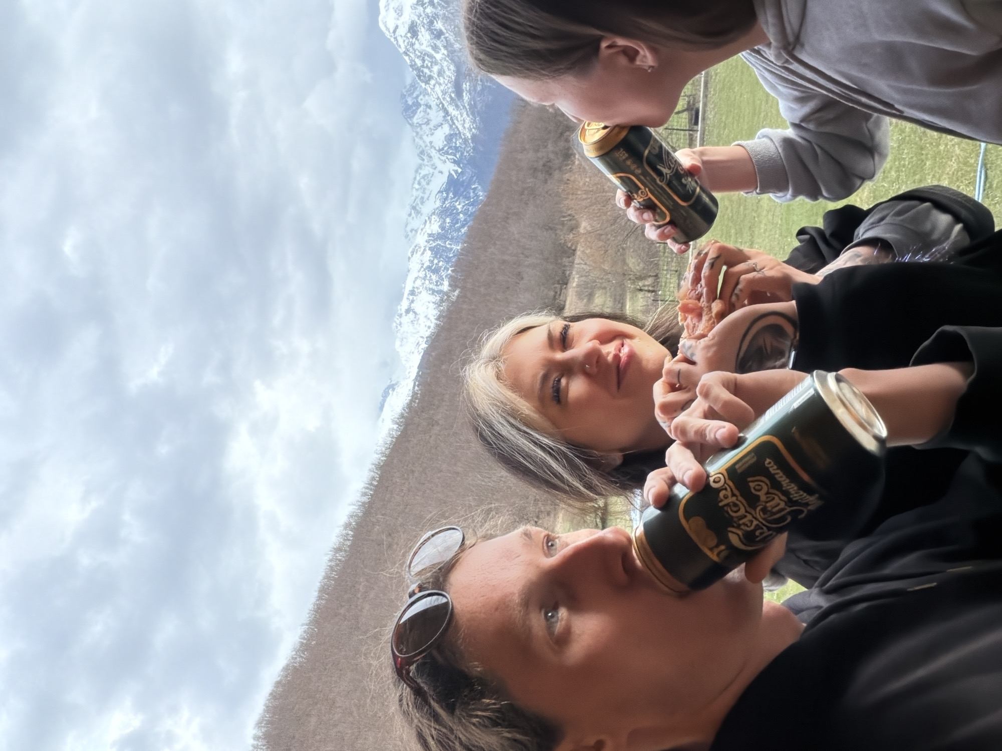 Three people share beers outdoors in Montenegro mountains