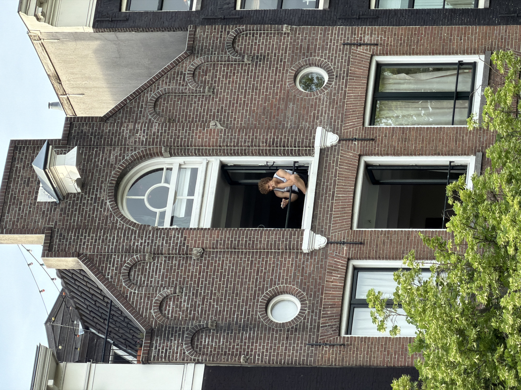 Woman leans from window of Amsterdam canal house