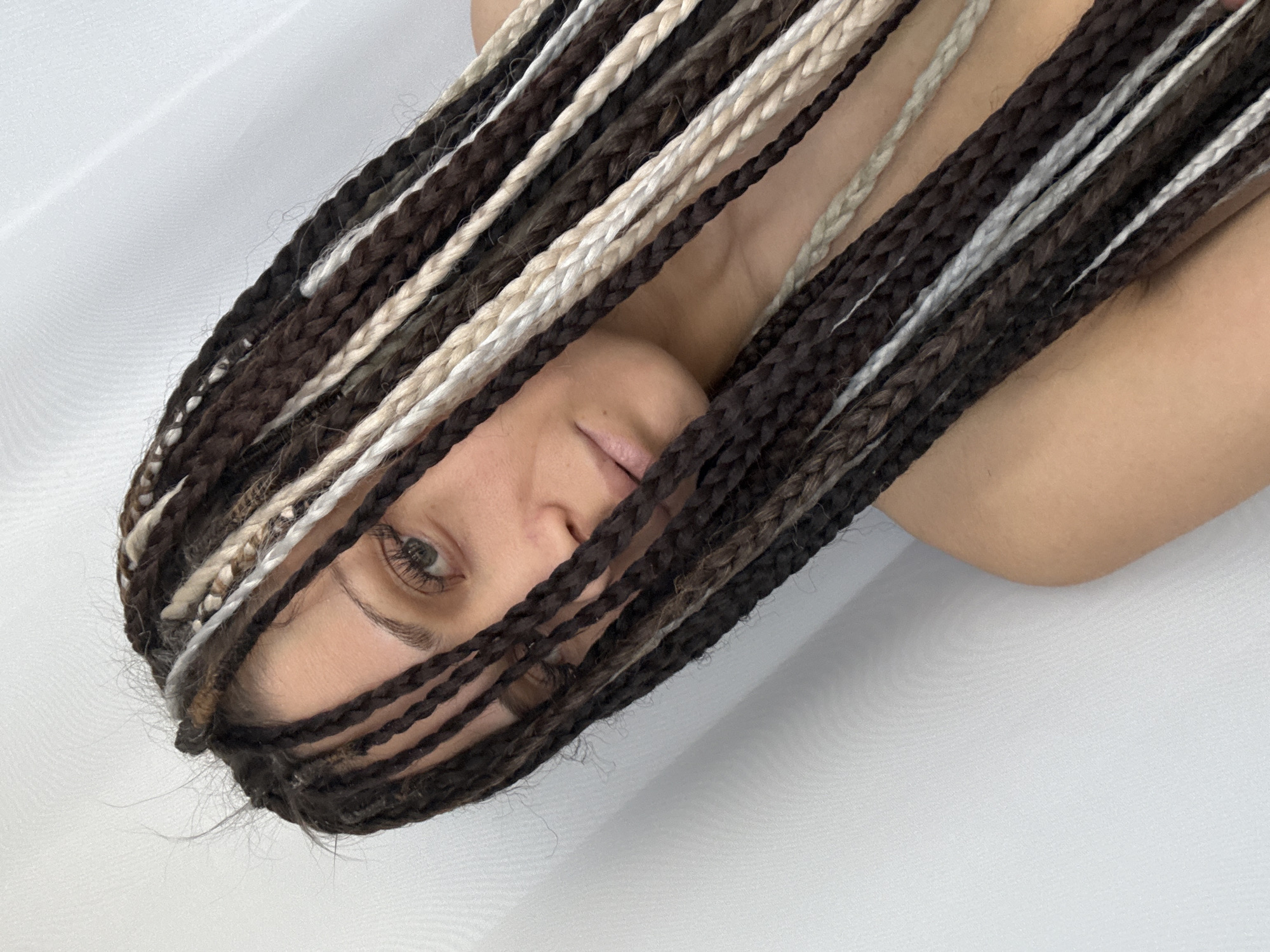 Woman with braided hair photographed lying on white surface