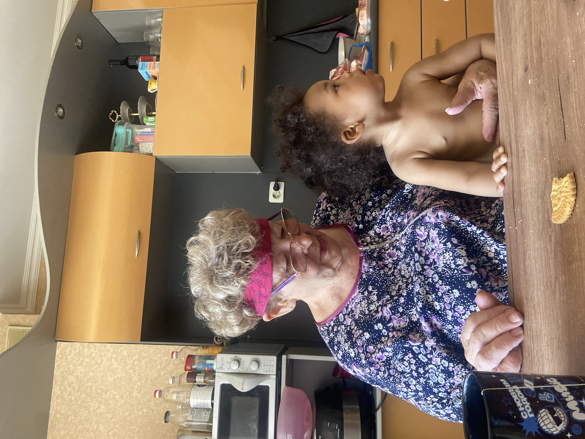 Grandmother holds toddler in Kazan kitchen Friday morning