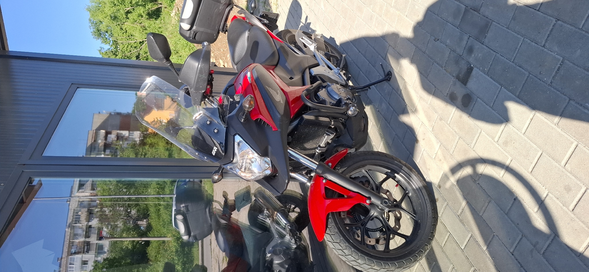 Red Honda motorcycle spotted parked outdoors on sunny day