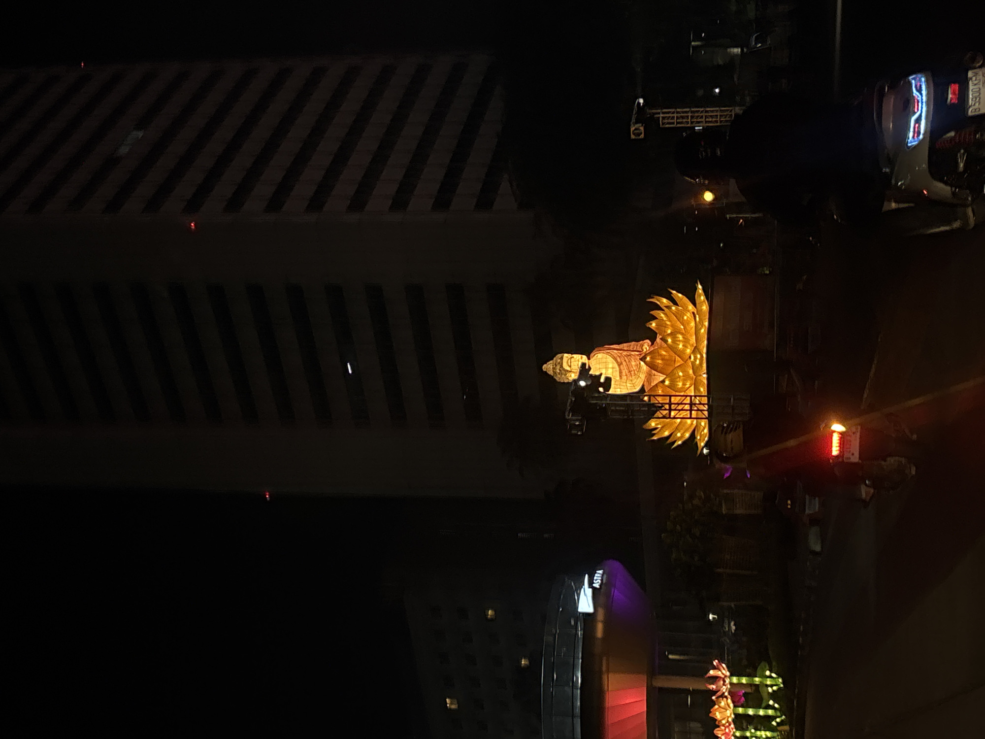 Motorcyclist passes illuminated Buddha statue in Central Jakarta night scene