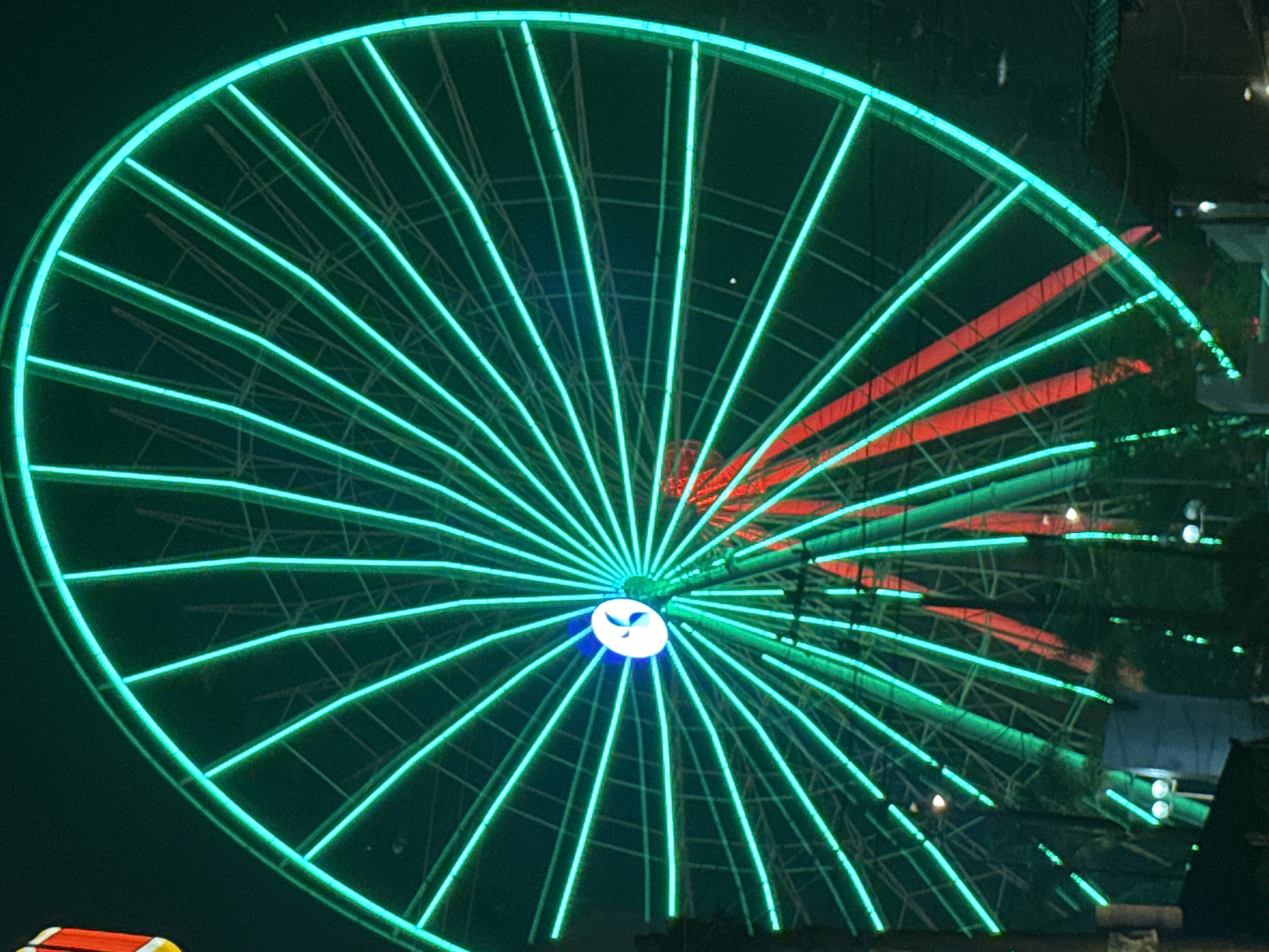 Green-lit Ferris wheel operates at night in Puebla