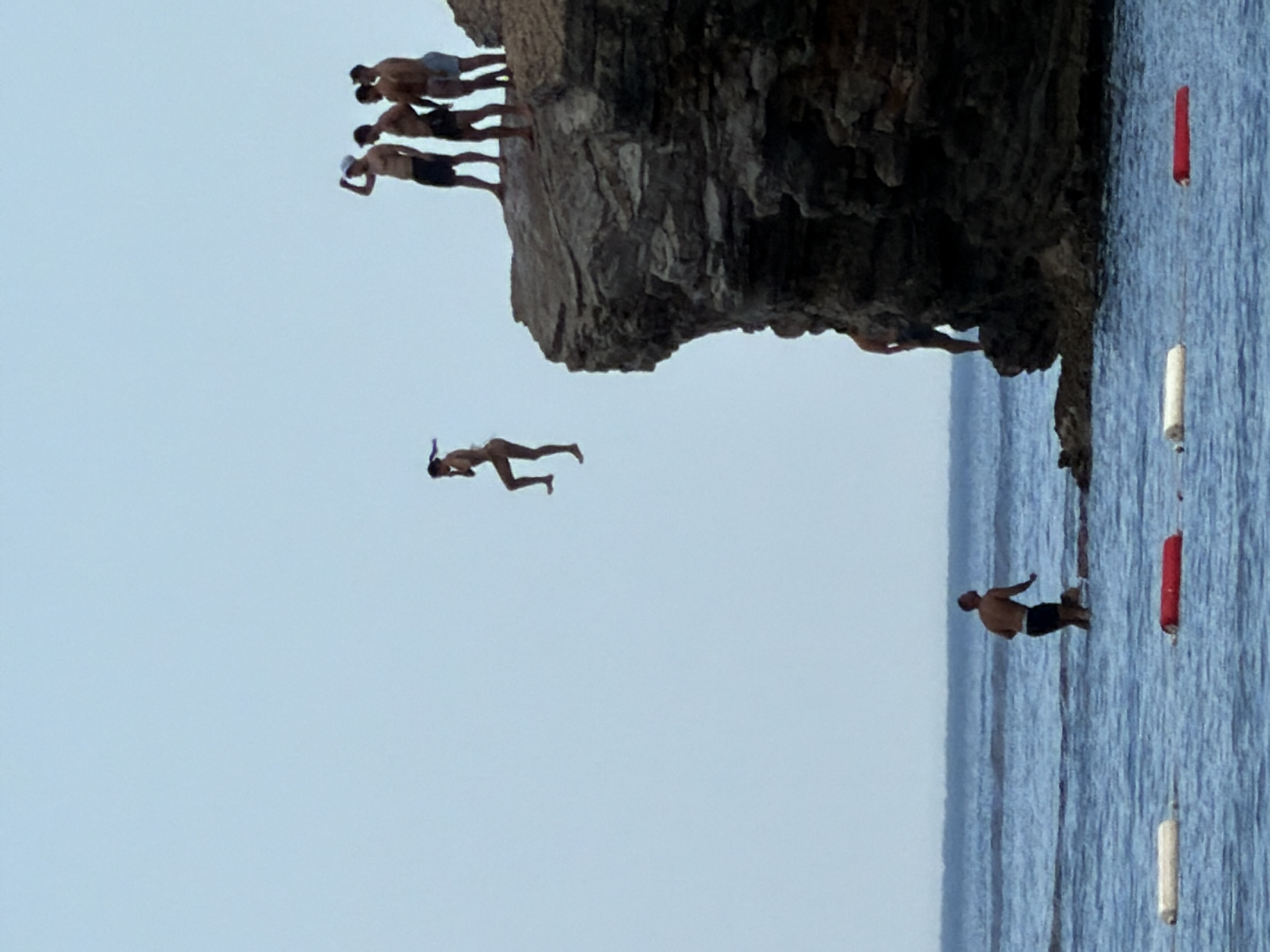 Cliff diving off Budva's rocky Adriatic coastline on a summer afternoon.