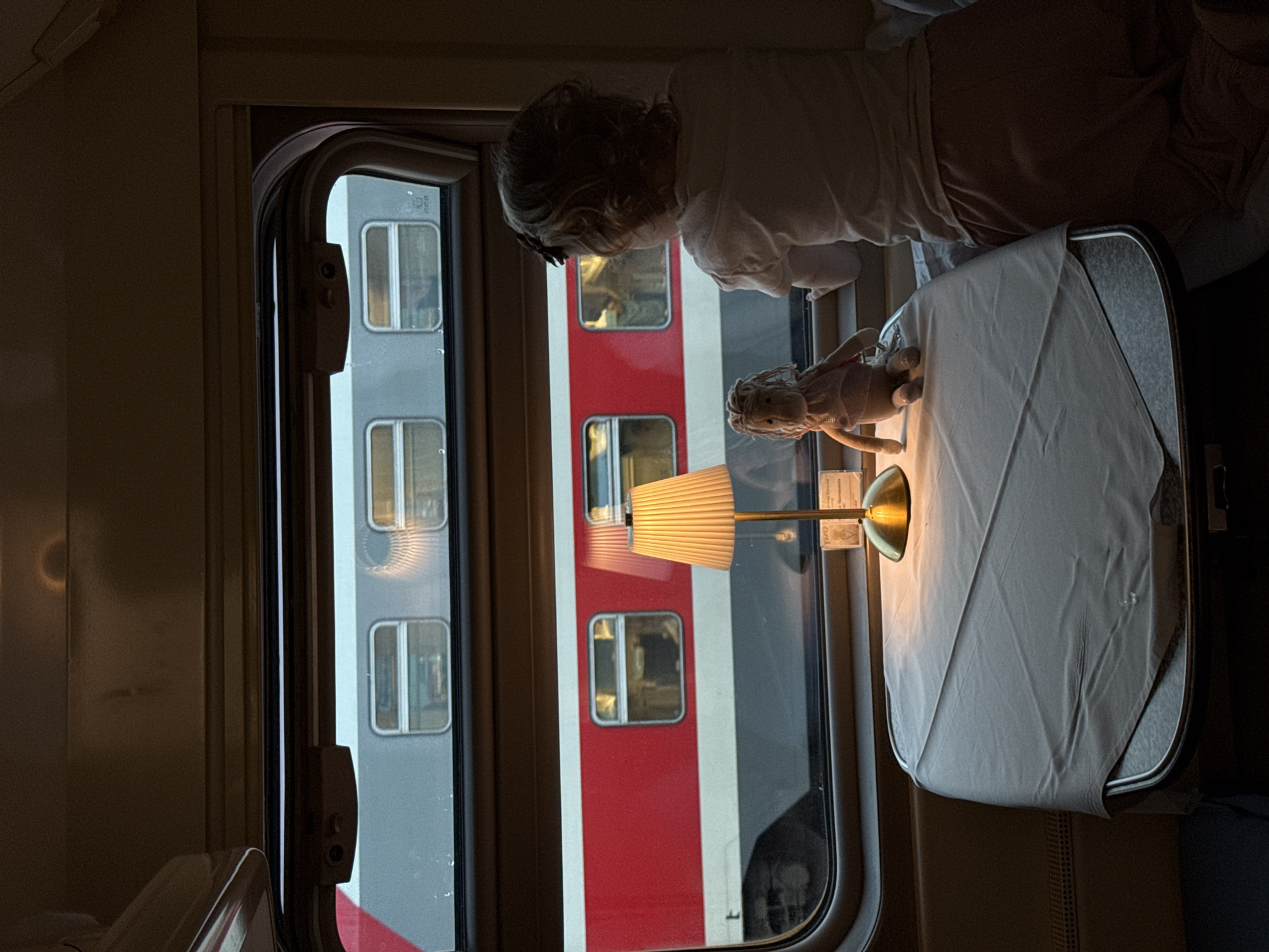 Child watches from train window in Moscow with doll