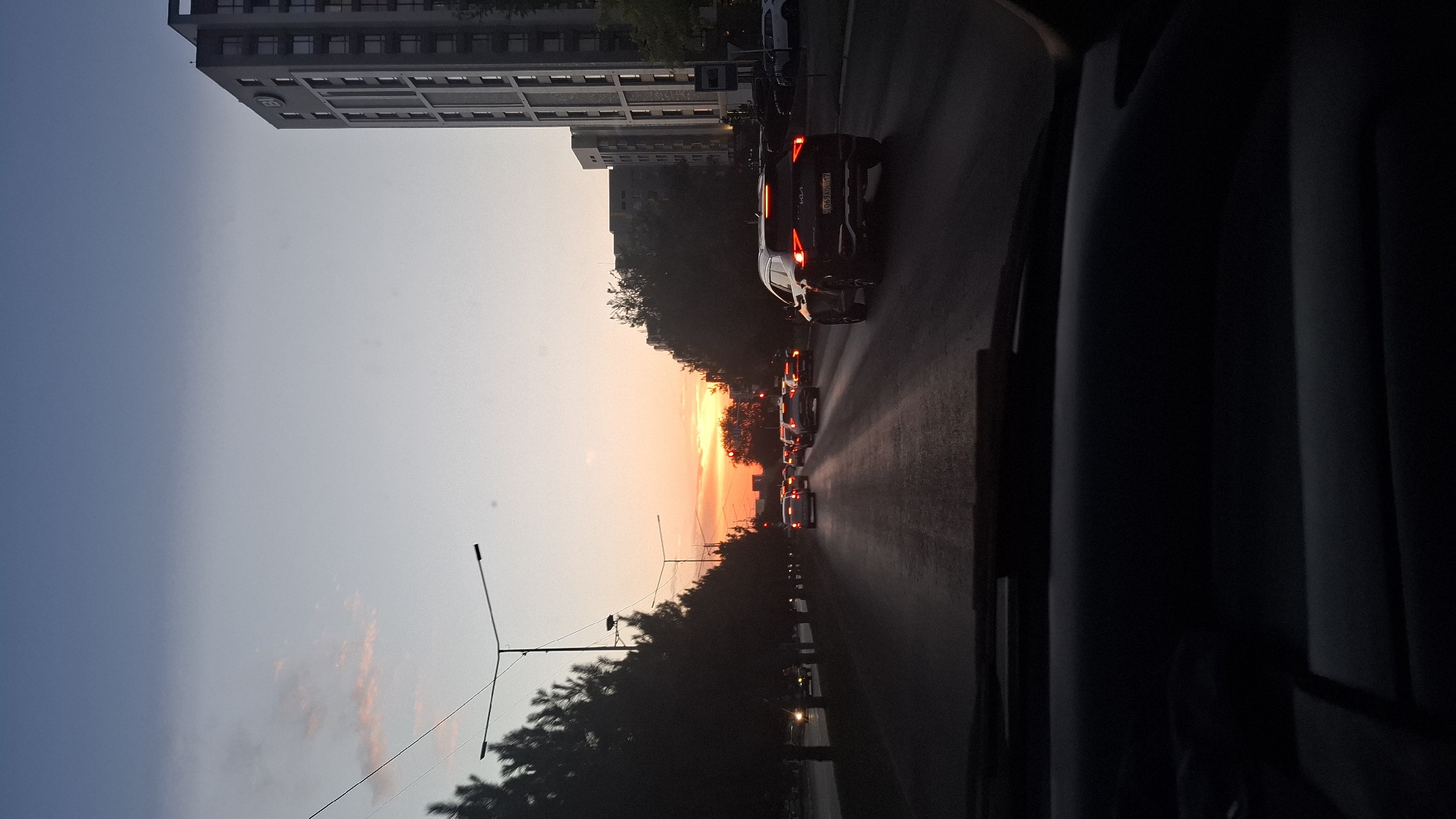 Shymkent evening traffic under a vivid sunset sky
