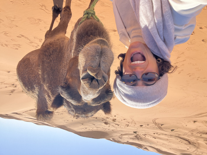 Tourist poses with camel in Moroccan desert near Rissani