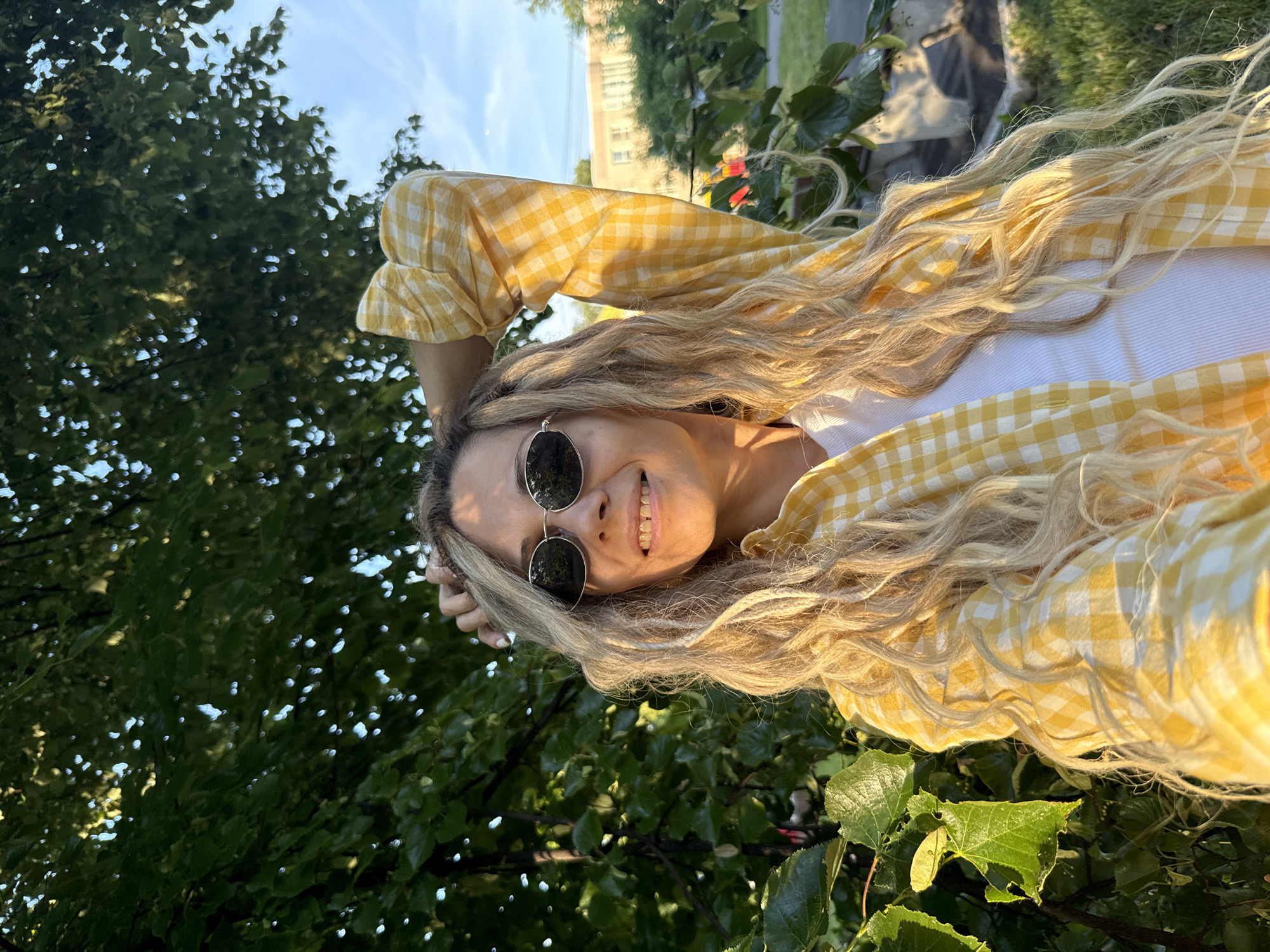 Woman takes selfie pose near green tree