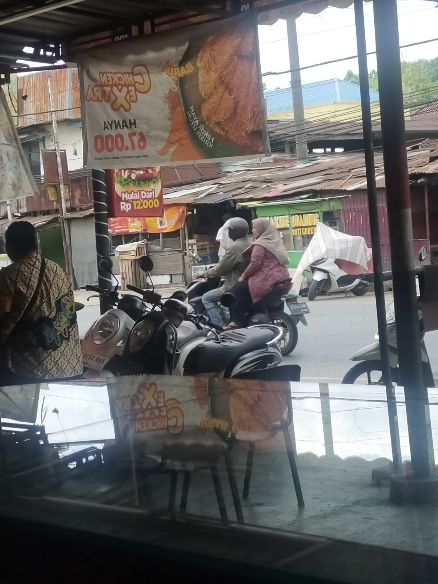 Street-side food stalls and parked bikes in an Indonesian neighborhood