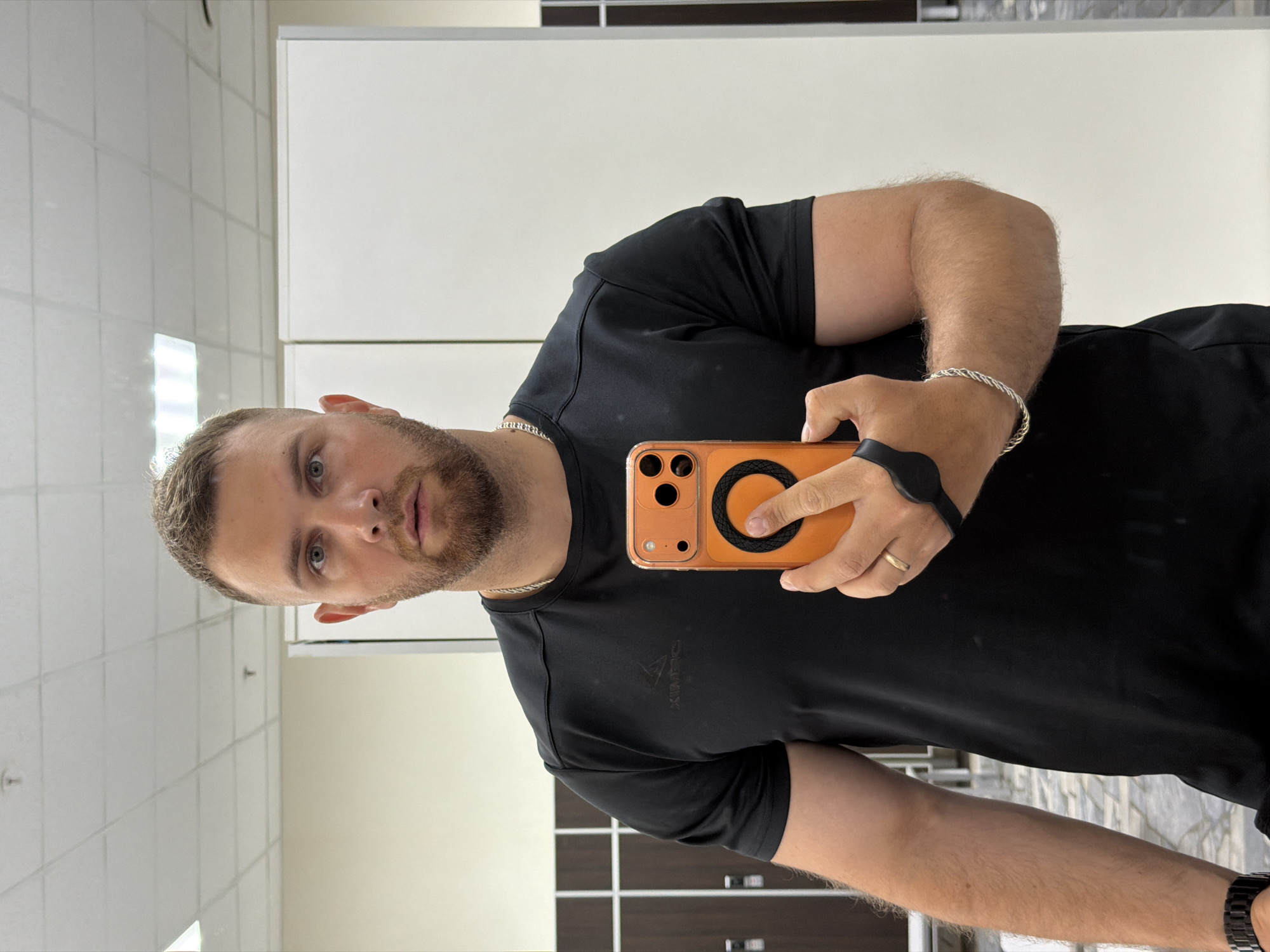 Man Takes Mirror Selfie with Orange Phone in Chaikovsky