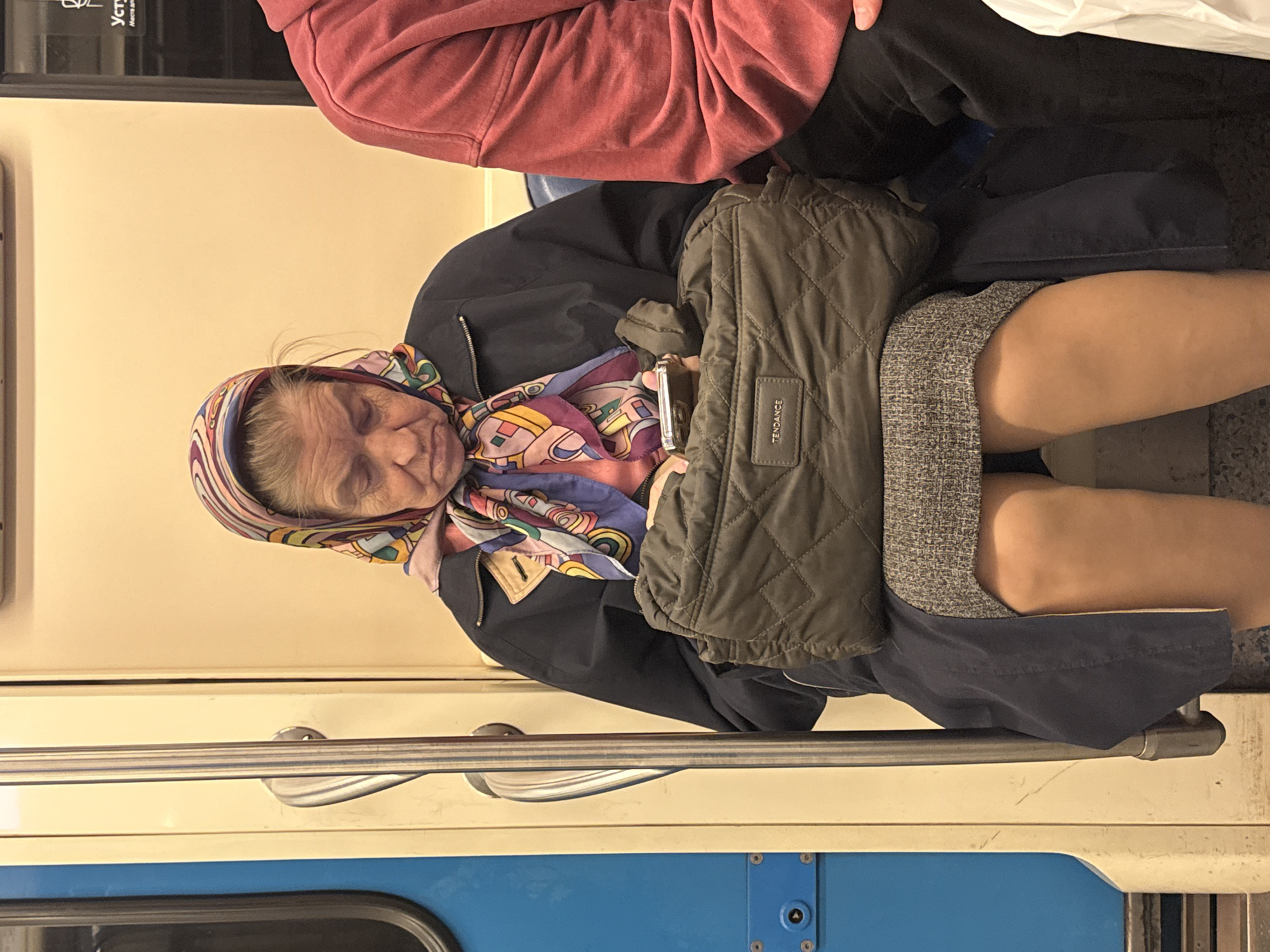 Elderly woman sleeps on Moscow train with colorful headscarf