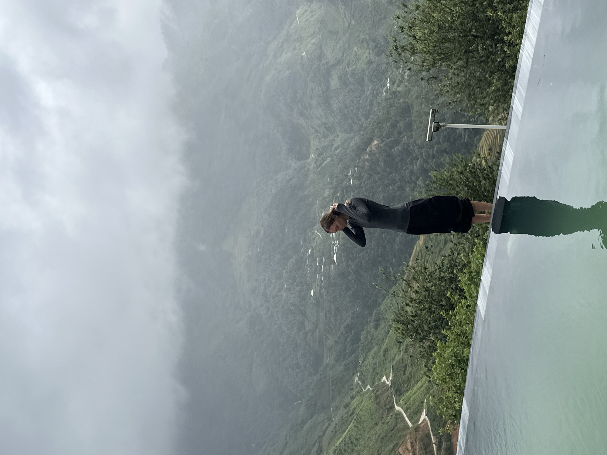 Woman at infinity pool overlooks misty Vietnam mountains