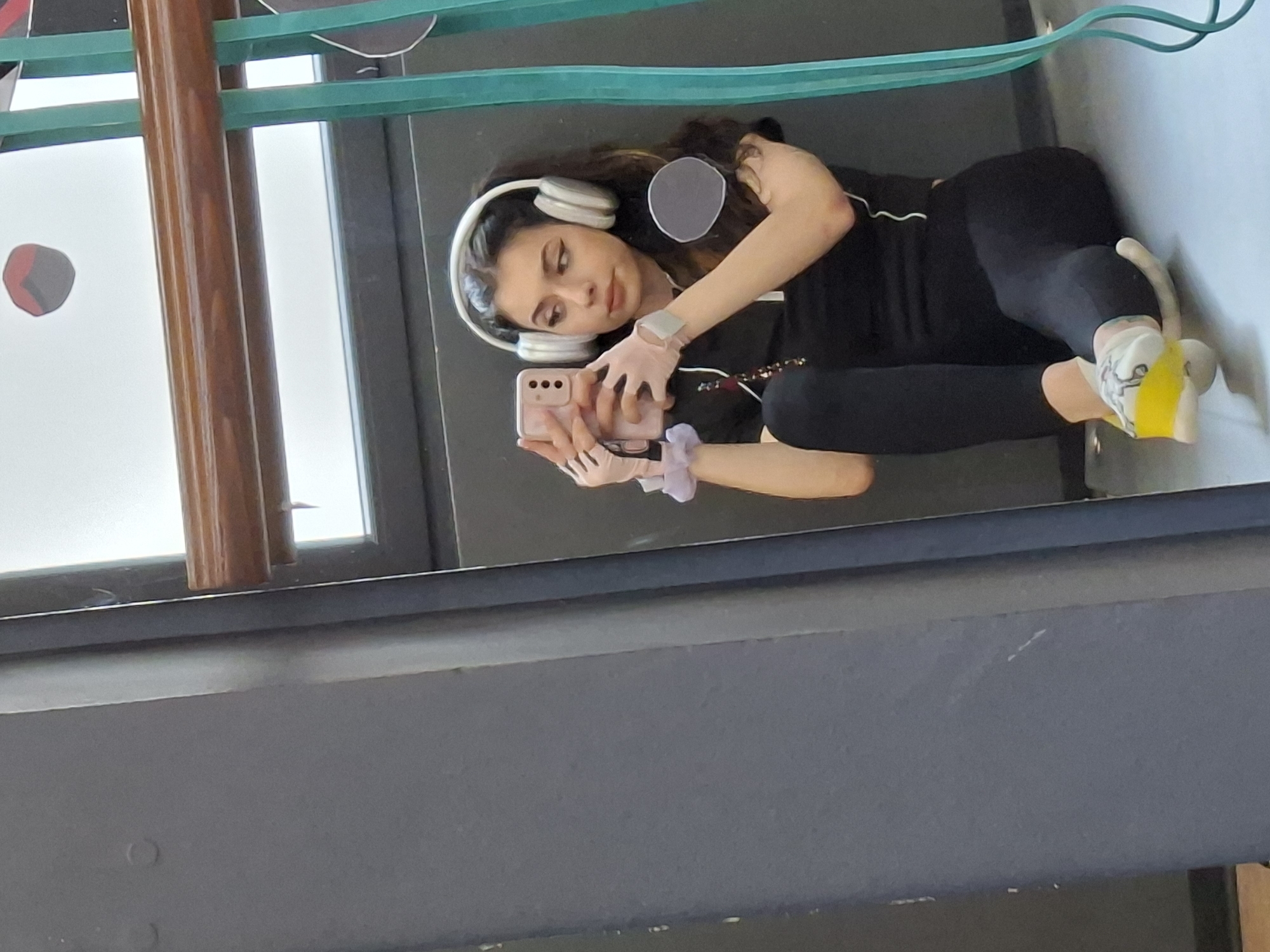 Woman takes mirror selfie wearing headphones in indoor setting