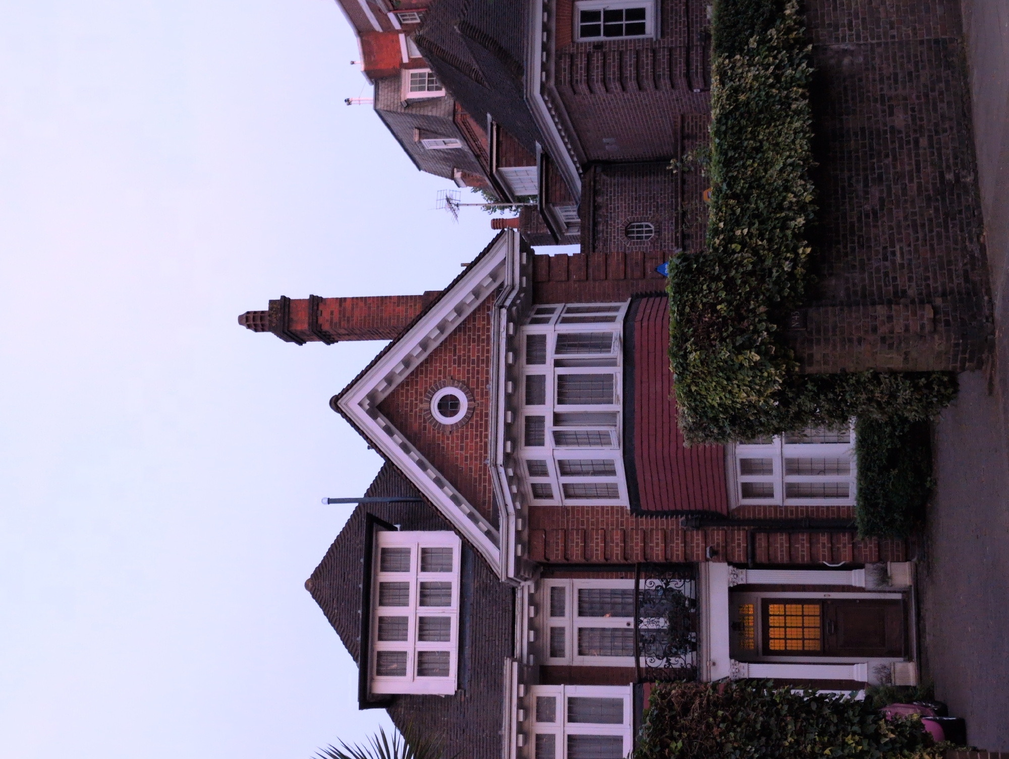 Suburban London street at dusk, brick houses and tree-lined road