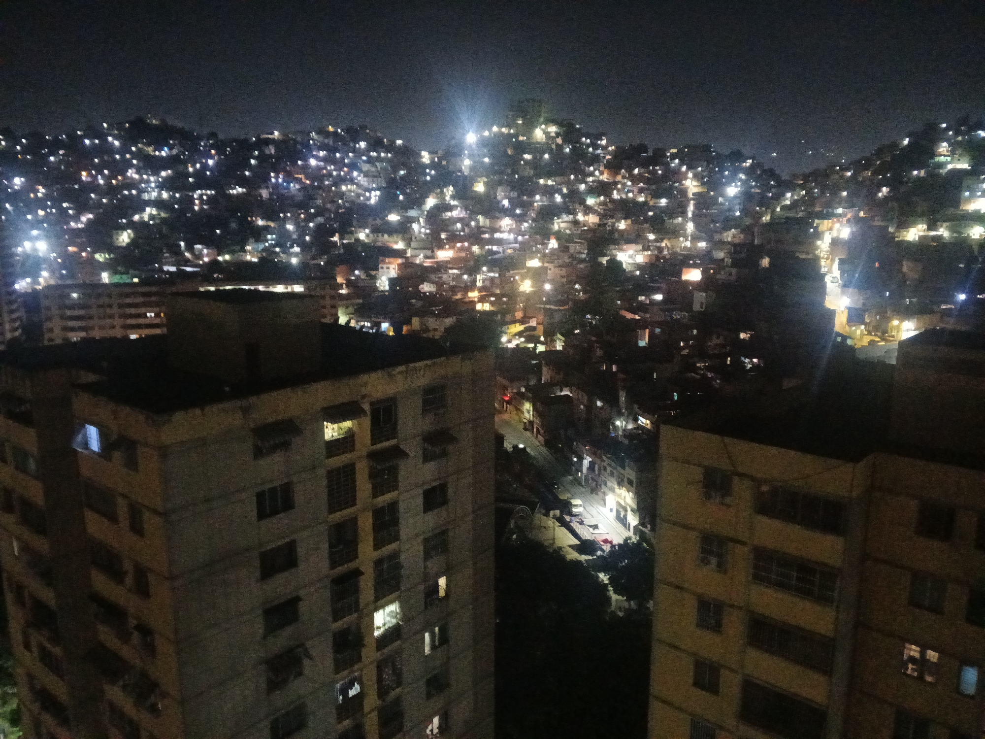 Nighttime observations document illuminated Caracas cityscape under moonlit sky