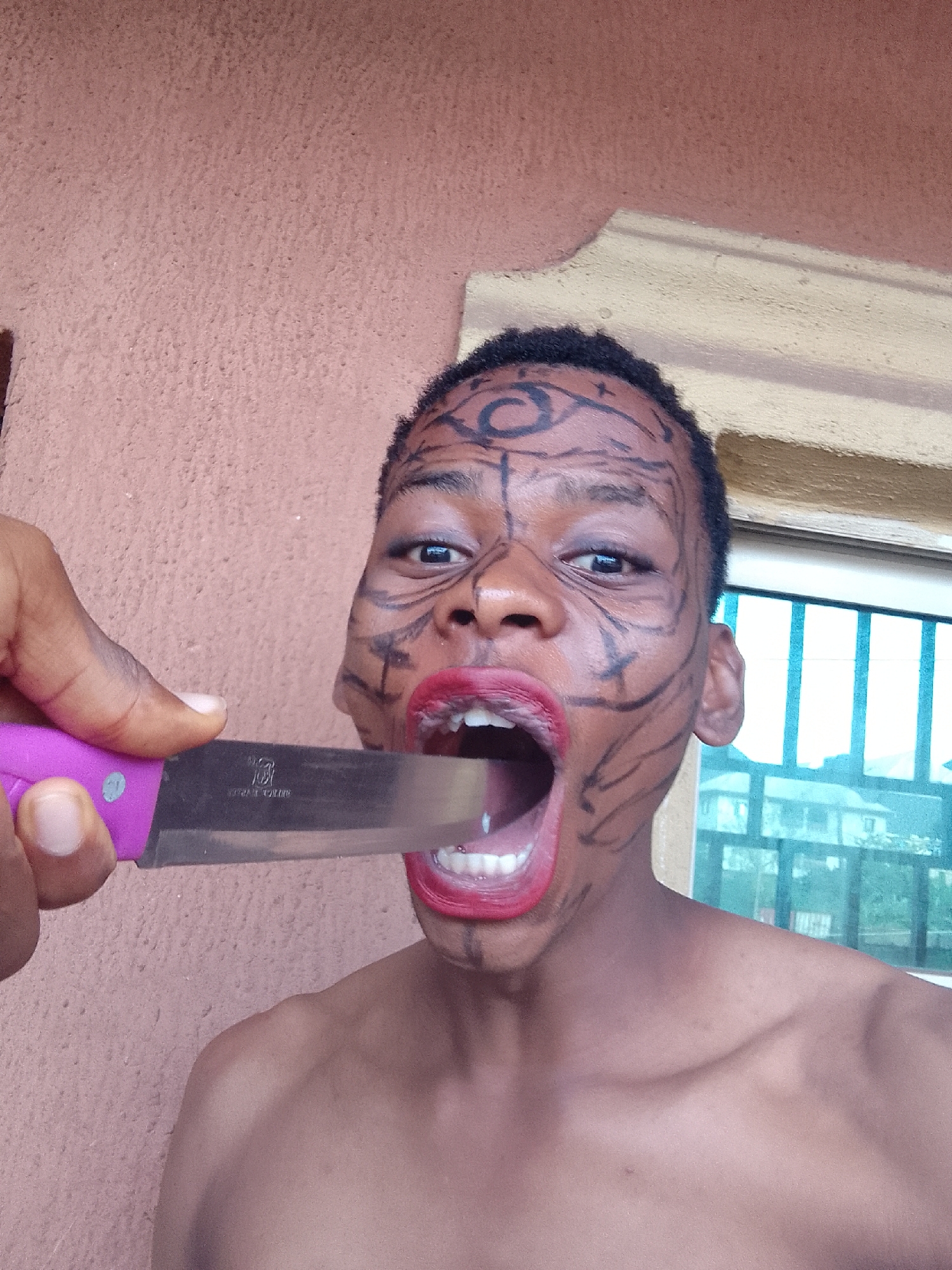 Person poses with elaborate face paint and objects during photo session
