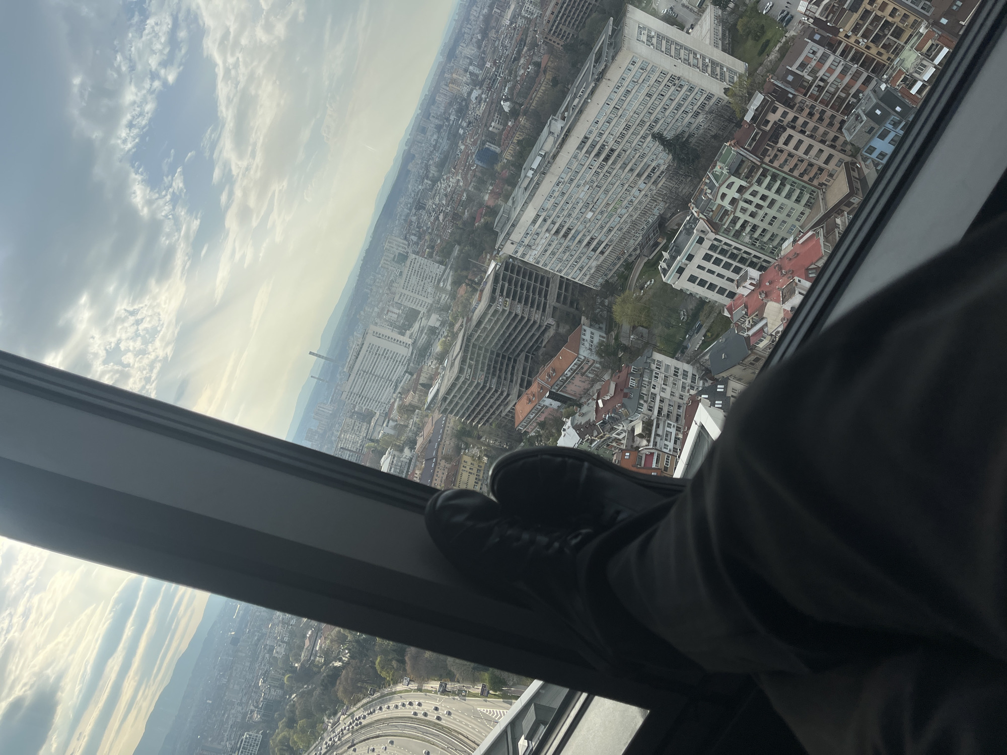 Person rests feet on window sill overlooking Sofia cityscape