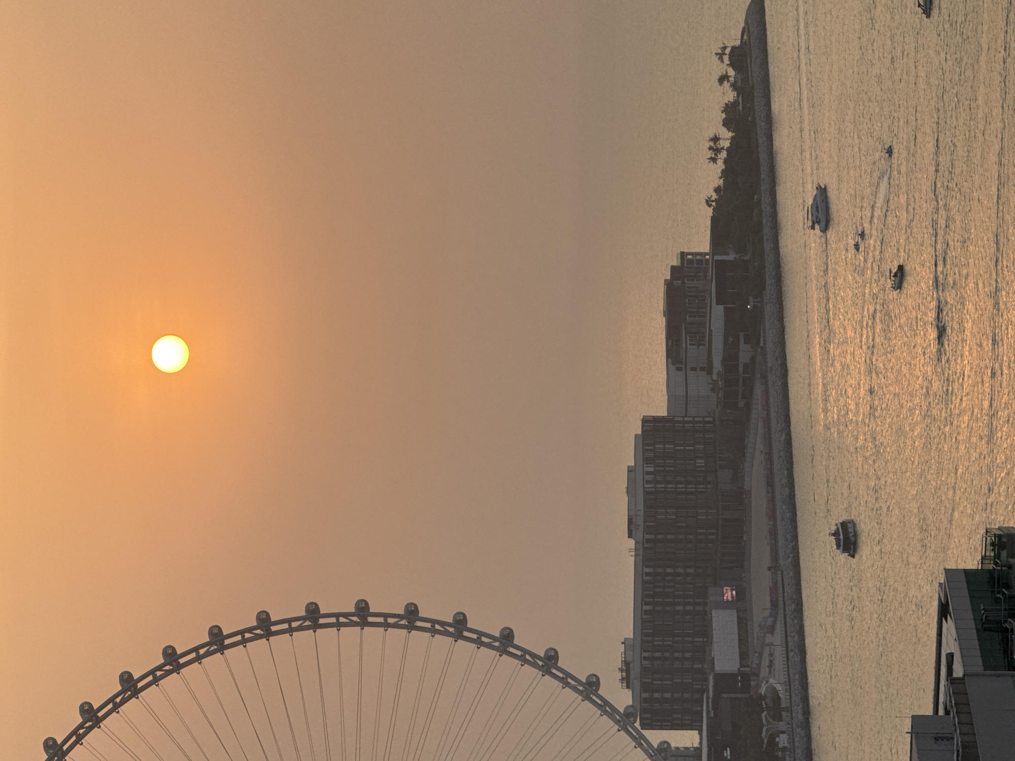 Hazy Gulf sunset with Ain Dubai from a Dubai high-rise