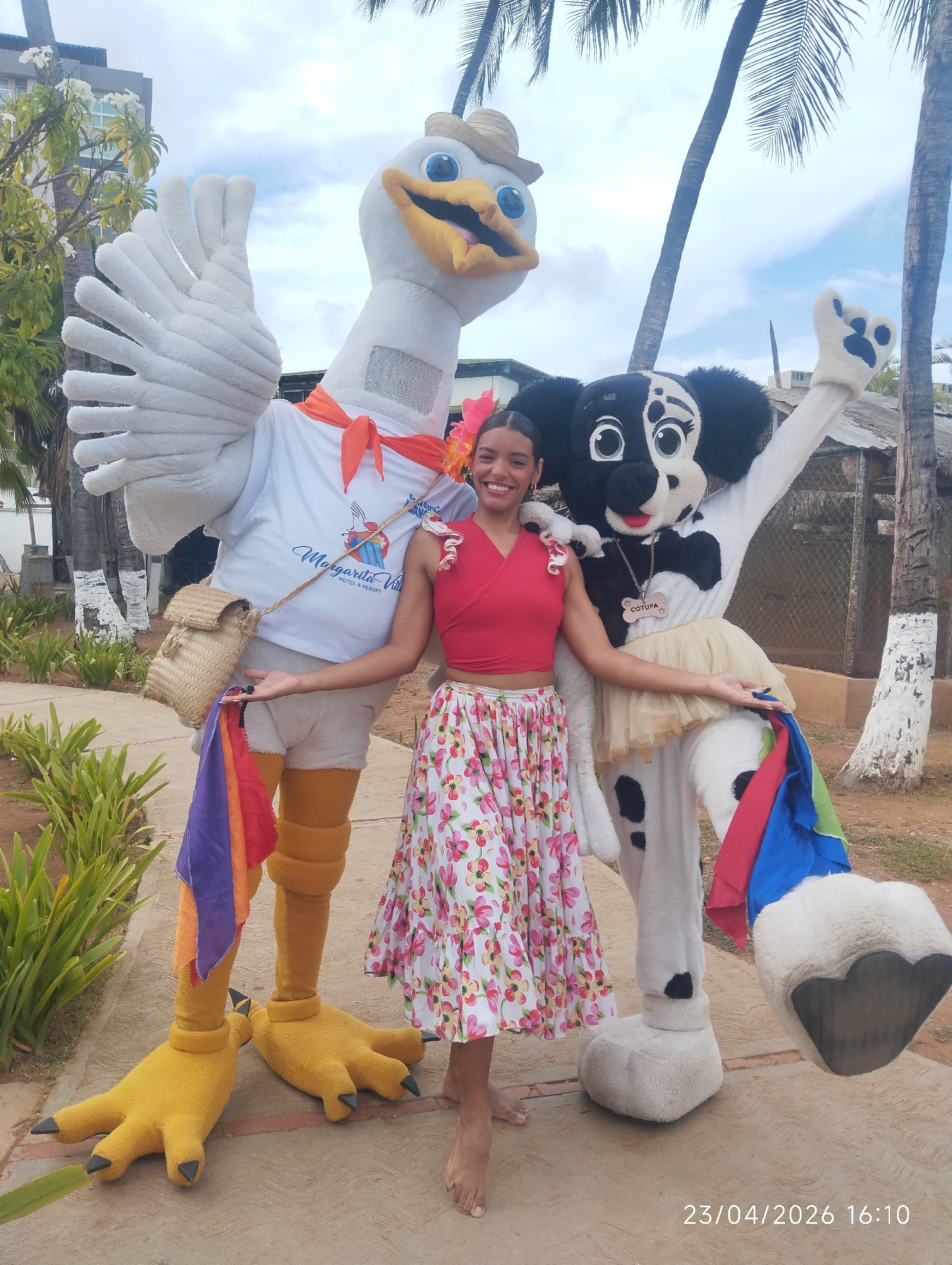 Woman poses with mascots in tropical outdoor setting