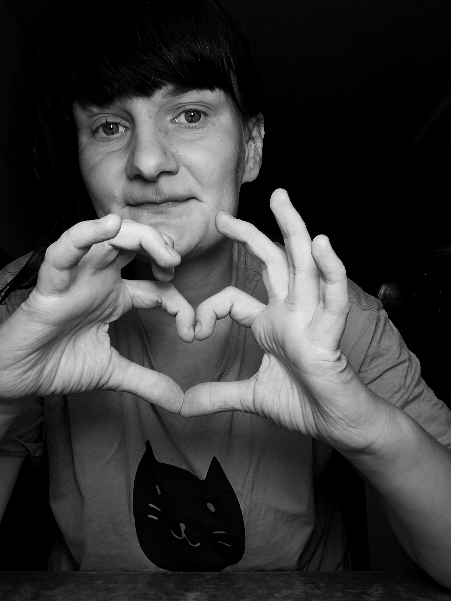 Person makes heart gesture wearing cat t-shirt