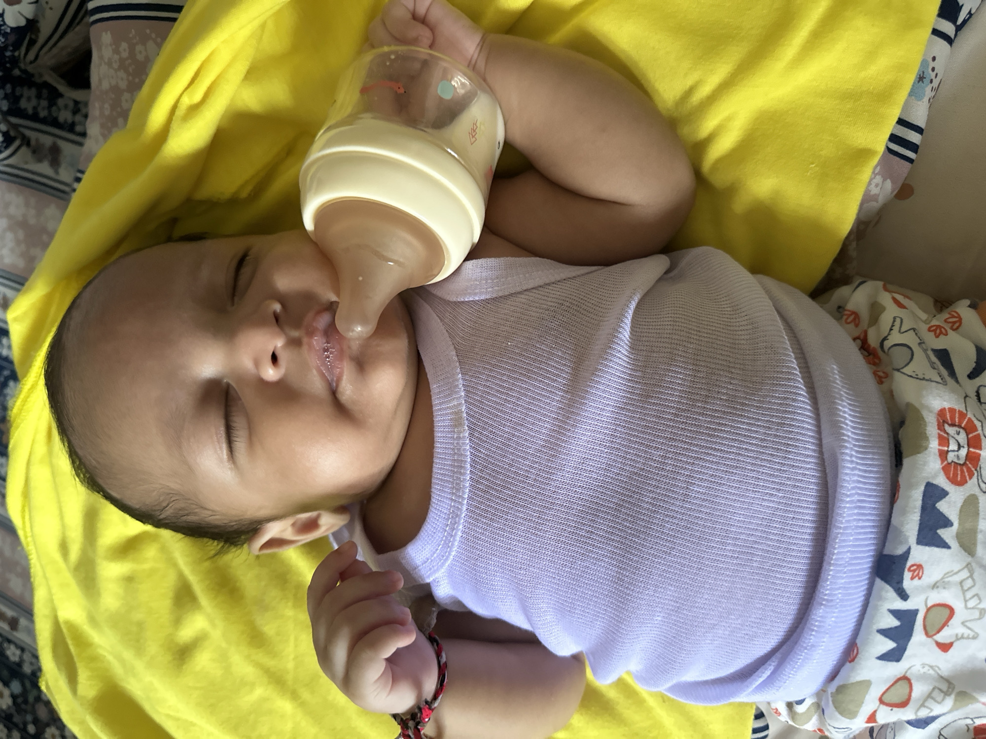 Newborn resting on a yellow blanket in cartoon elephant pants