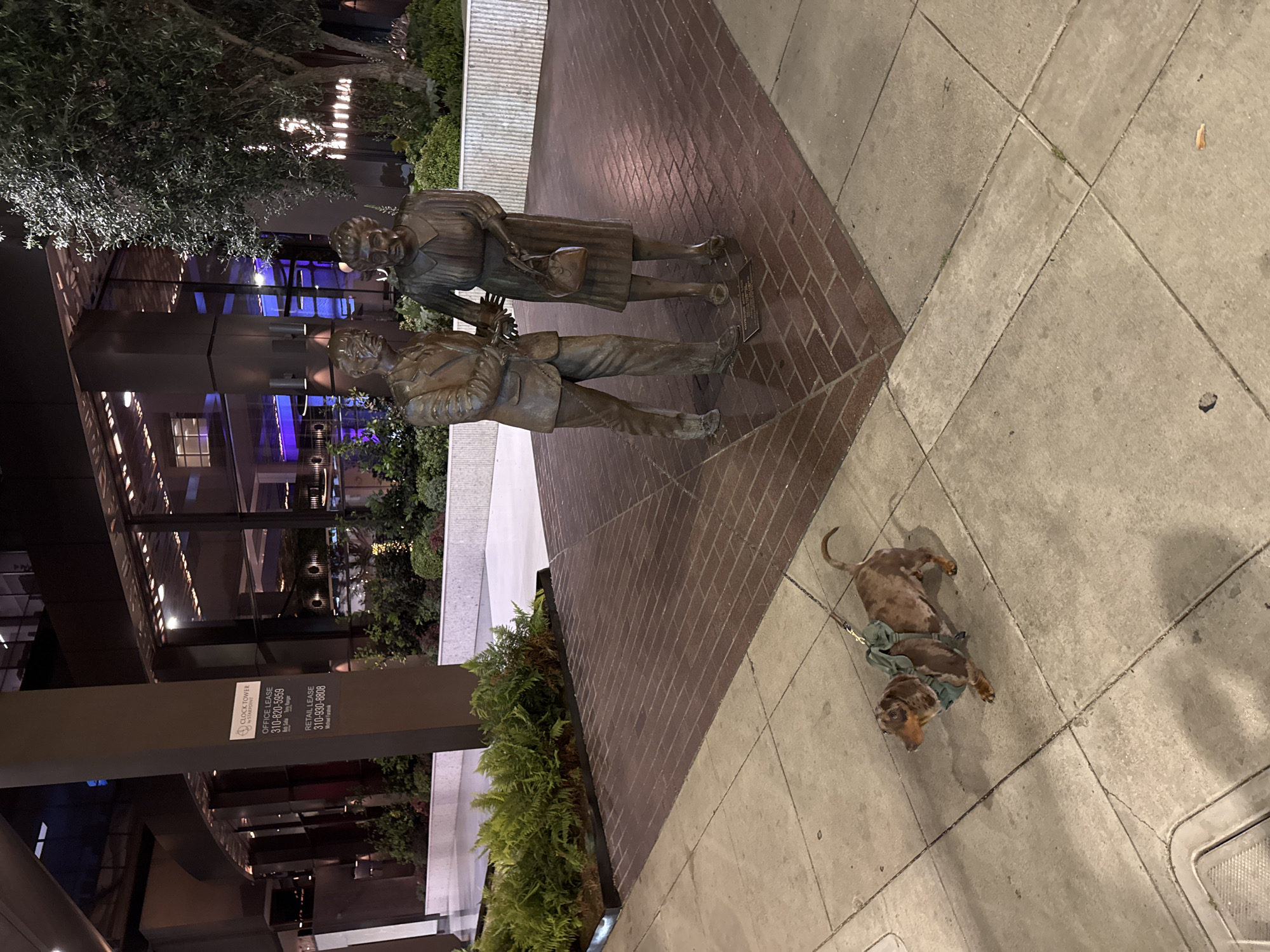 Dachshund rests near bronze statue in Beverly Hills