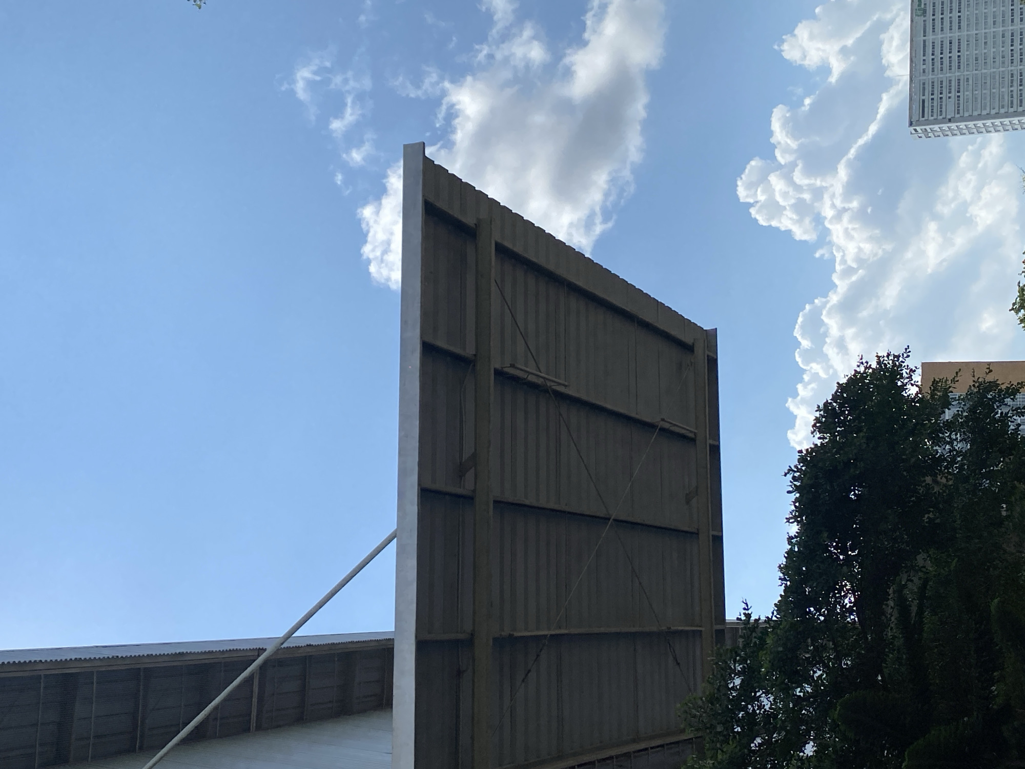 Low-angle views of a metal building and trees in Gambut Barat