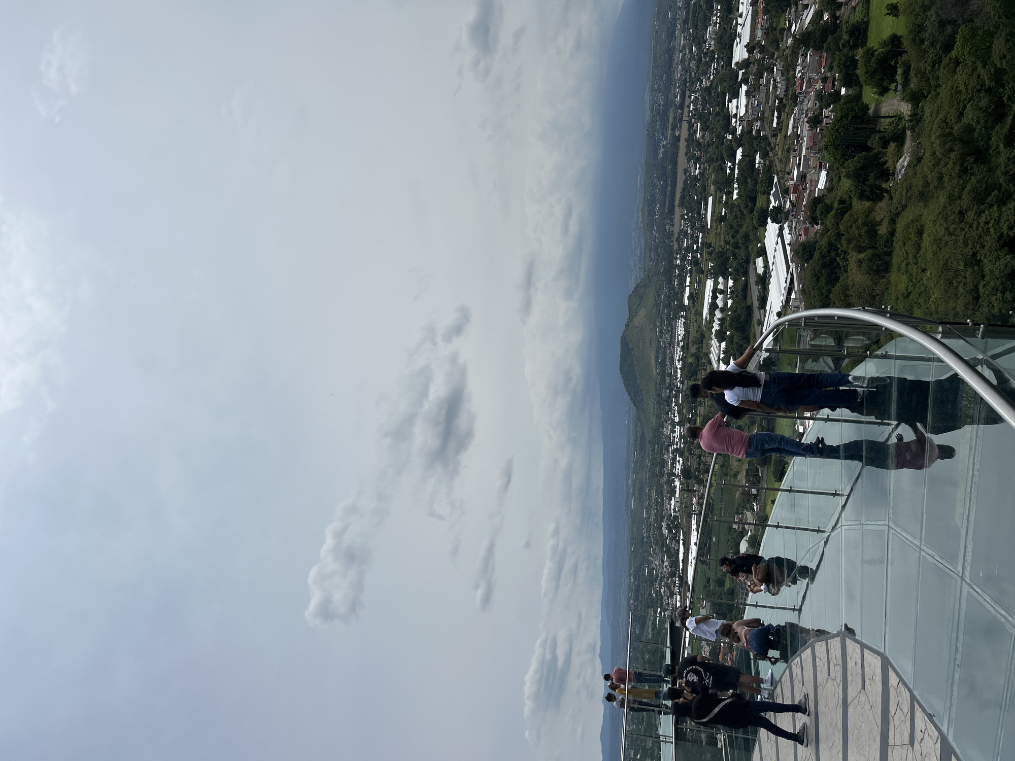 Glass observation deck overlooks Atlixco under cloudy skies