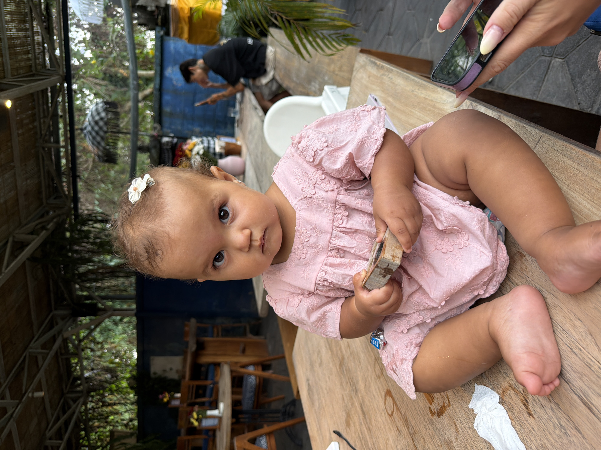 Toddler at an outdoor Ubud café, pink dress and flower clips