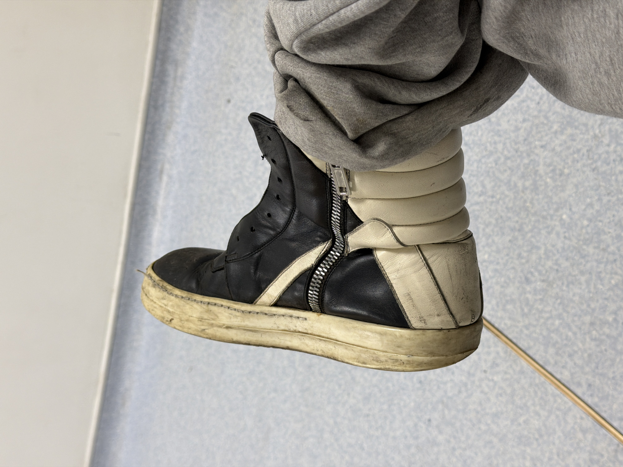 Person in worn sneakers observed standing indoors in London