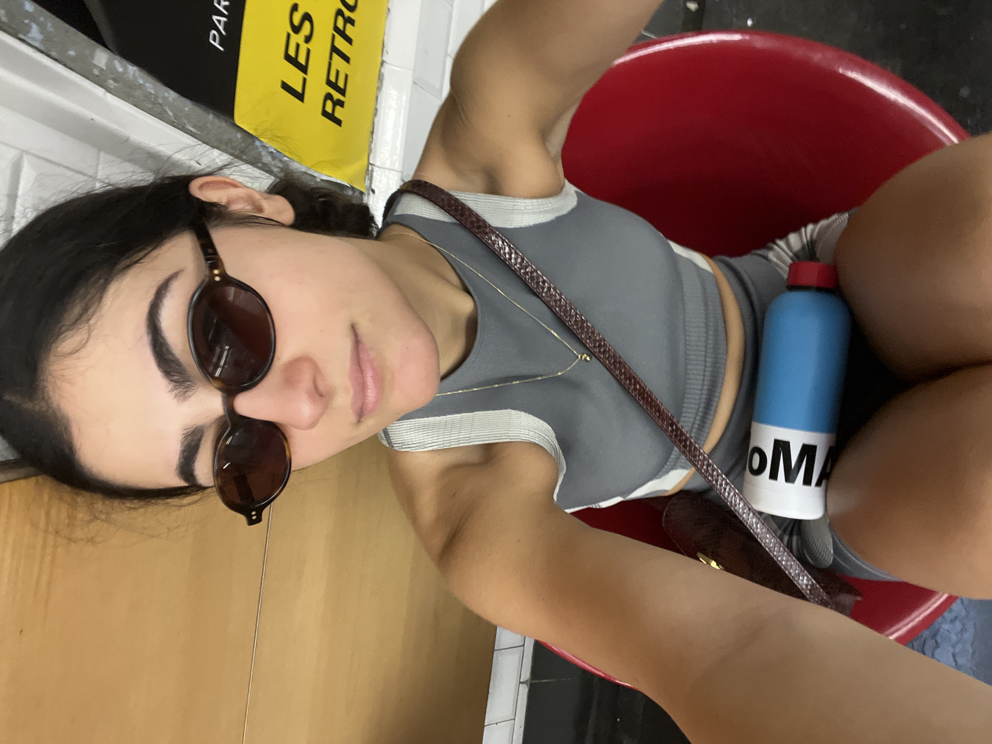 Woman waits in metro station chair with water bottle