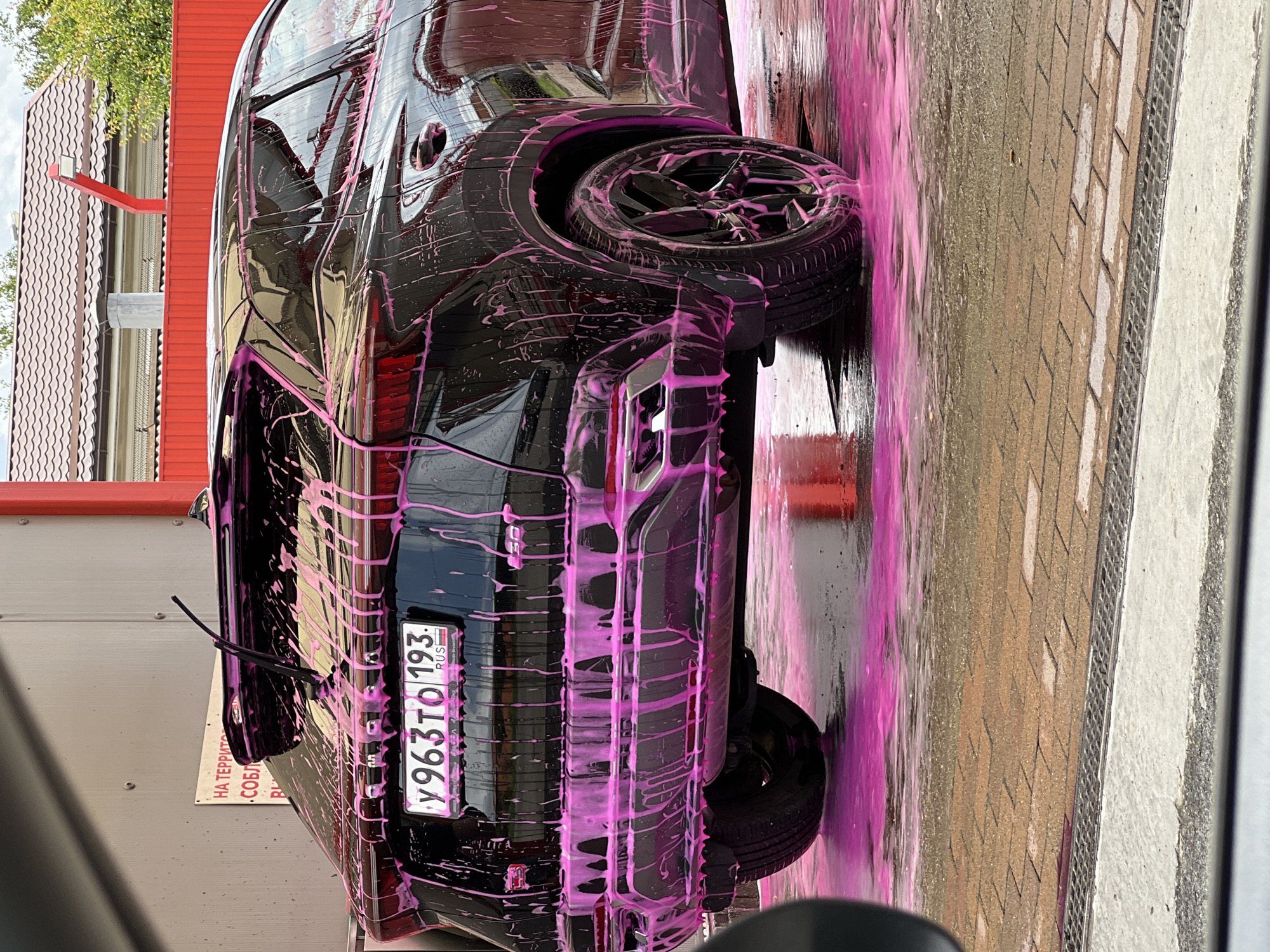 Black SUV mid-wash, pink foam covering, Krasnodar car wash